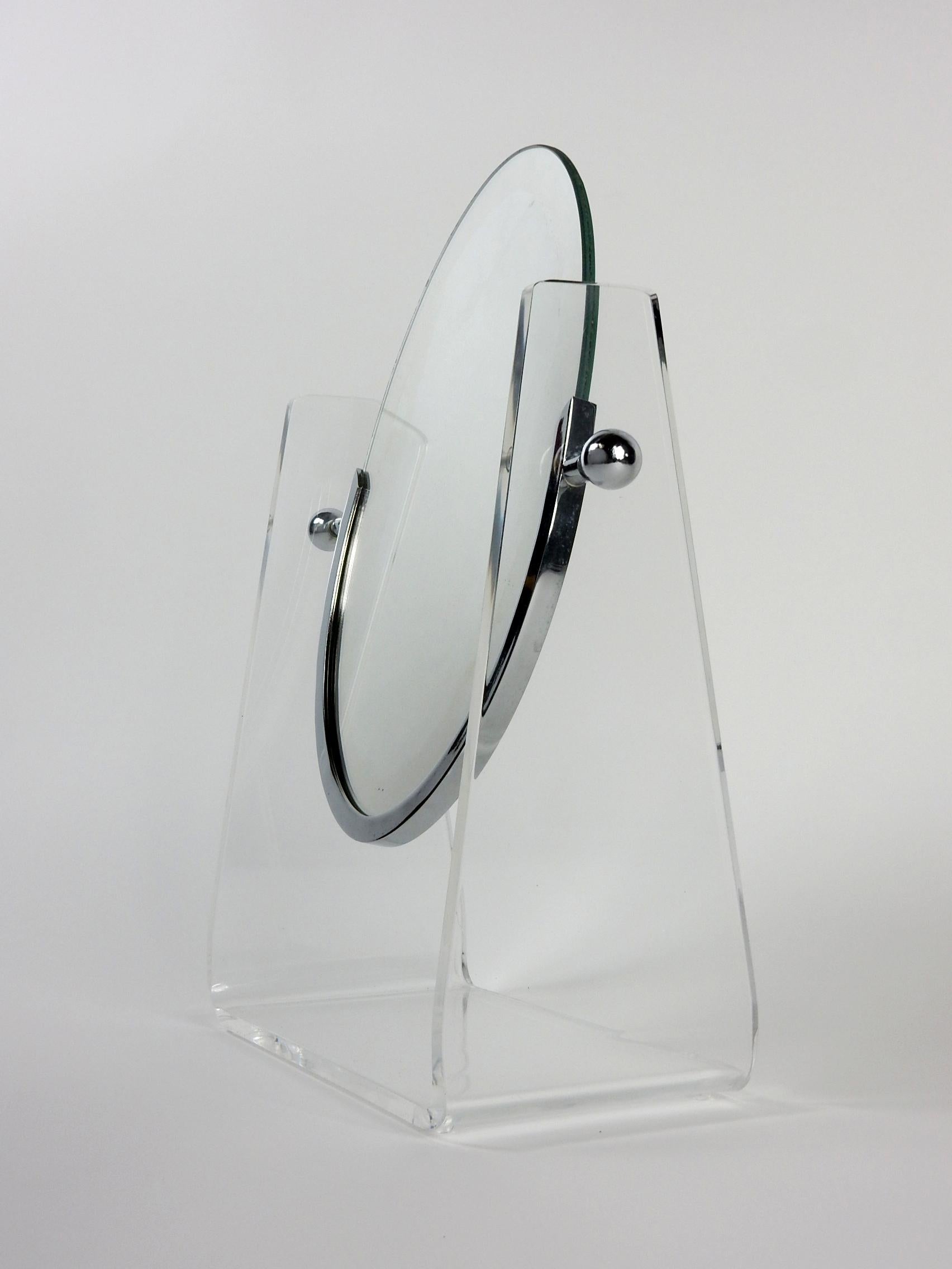 Beidseitiger Tischspiegel, entworfen von Charles Hollis Jones.
Ovaler Spiegel, aufgehängt in einem Ständer aus Lucite mit vernickeltem Rahmen und Kugelverstellern.
Schwenkbar in der Mitte mit Einstellkugeln, um den gewünschten Winkel zu