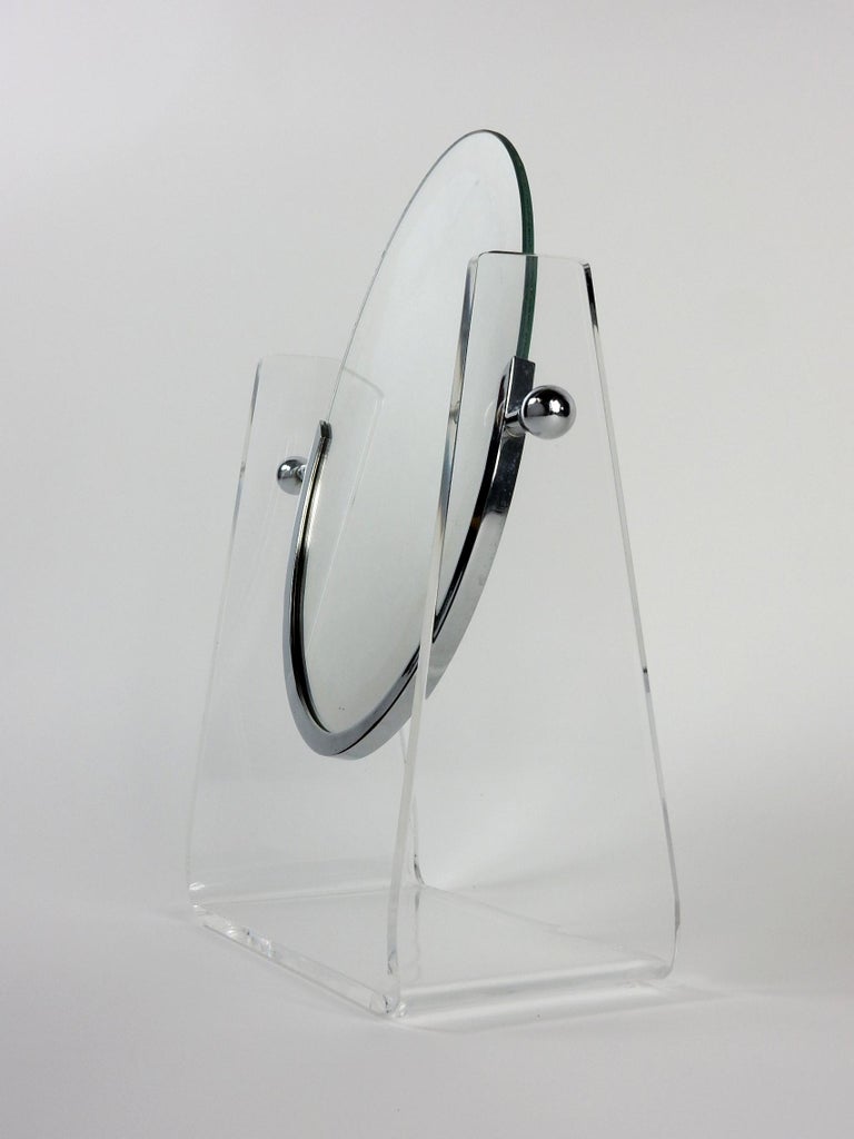 Double sided table mirror designed by Charles Hollis Jones.
Oval mirror suspended inside a Lucite stand with nickel-plated frame and ball adjusters.
Pivots at center with adjusting balls to hold desired angle.
Really nice clean example with no