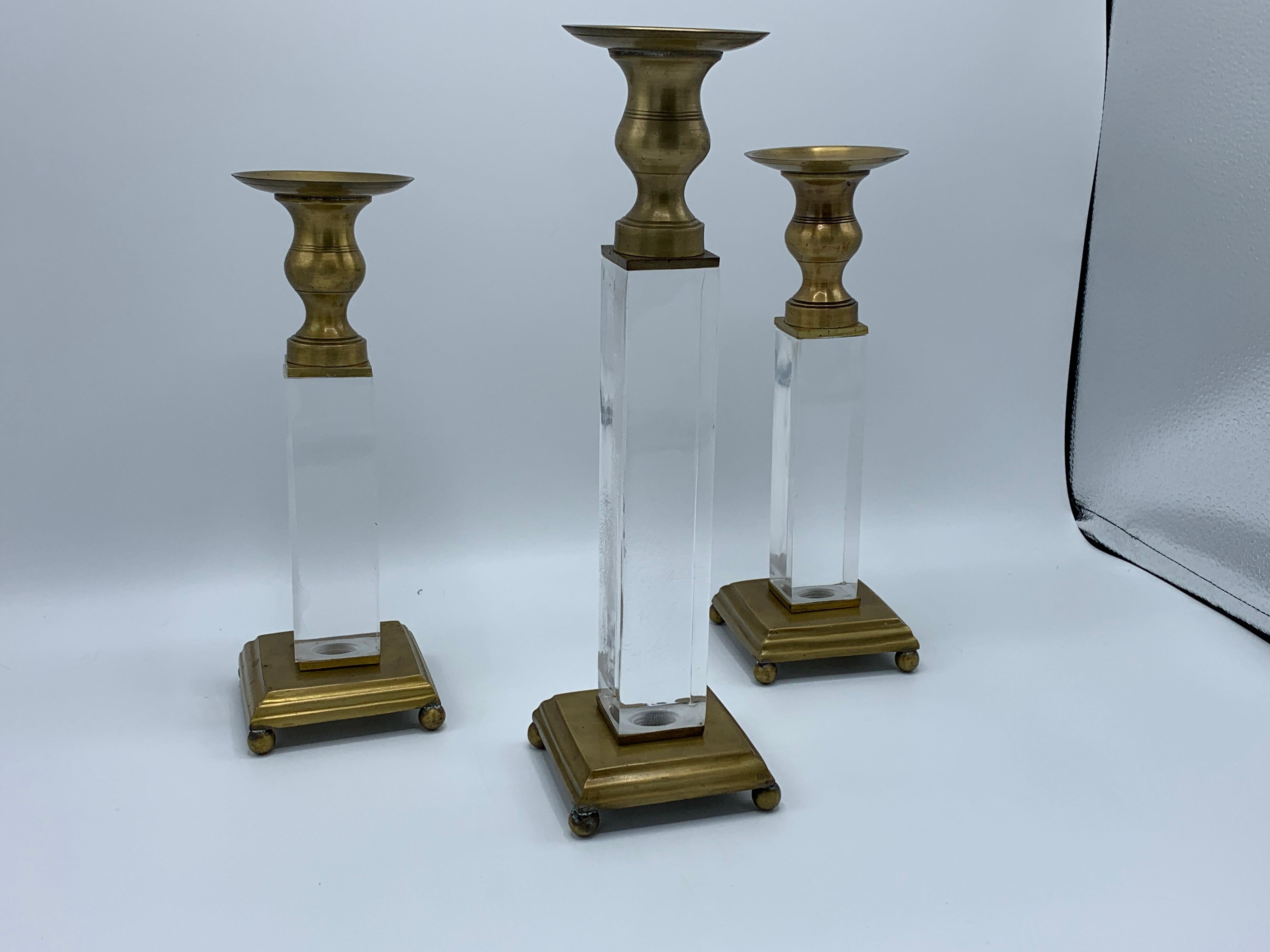 Listed is a gorgeous, set of three, 1970s Charles Hollis Jones style Lucite and brass candlesticks. Large(x1); 3.5in D x 3.5in W x 12.5in H. Small(x2); 3.5in D x 3.5in W x 10.25in H. Each Lucite block is 1.5in thick. Heavy, 5.5lbs for the entire set.