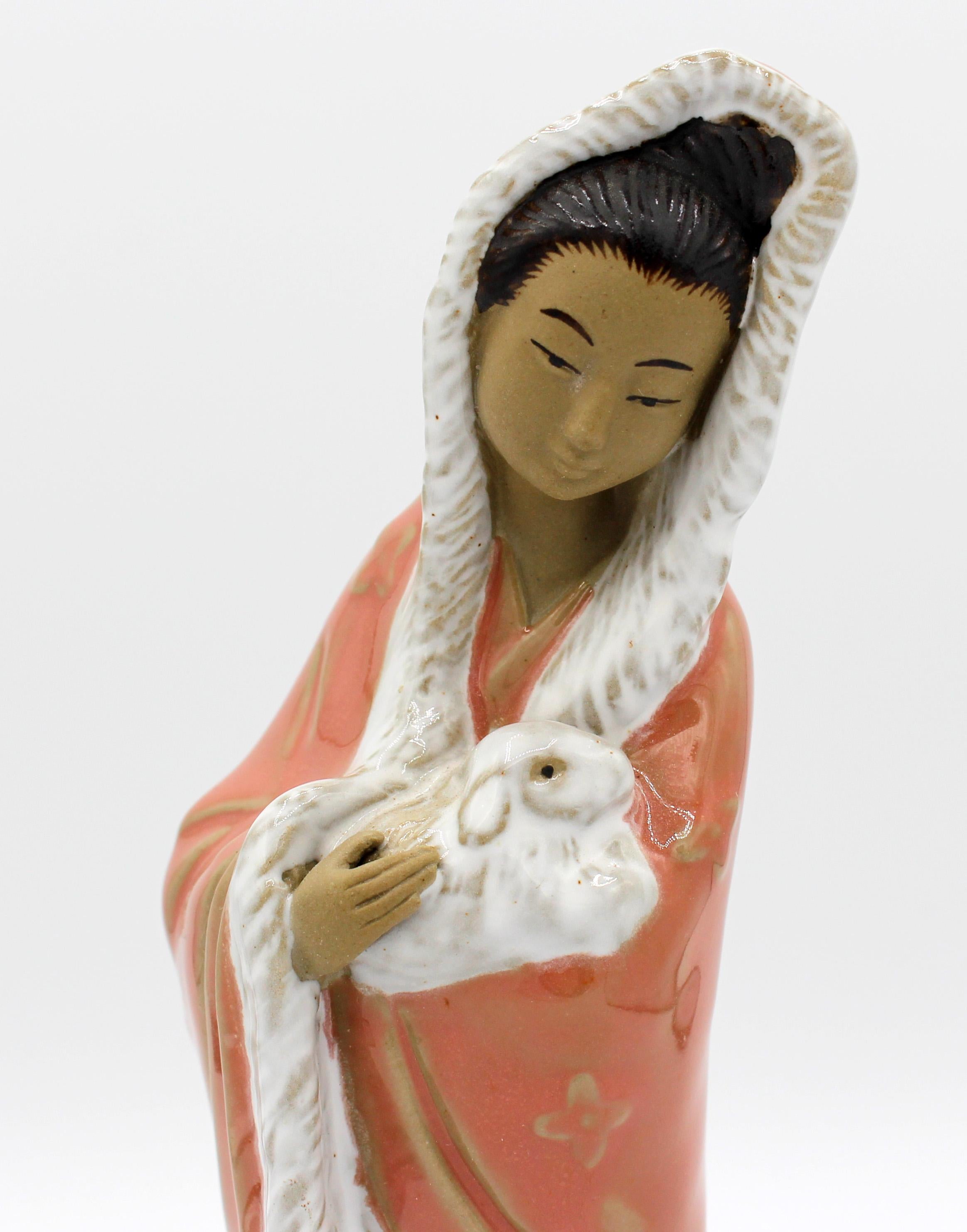 Chinese, circa 1970s, mud figure from Wanjiang, Guangong province. A lovely woman in a winter fur trimmed coat holding a rabbit with a goat at her feet. Finely detailed. 9.5