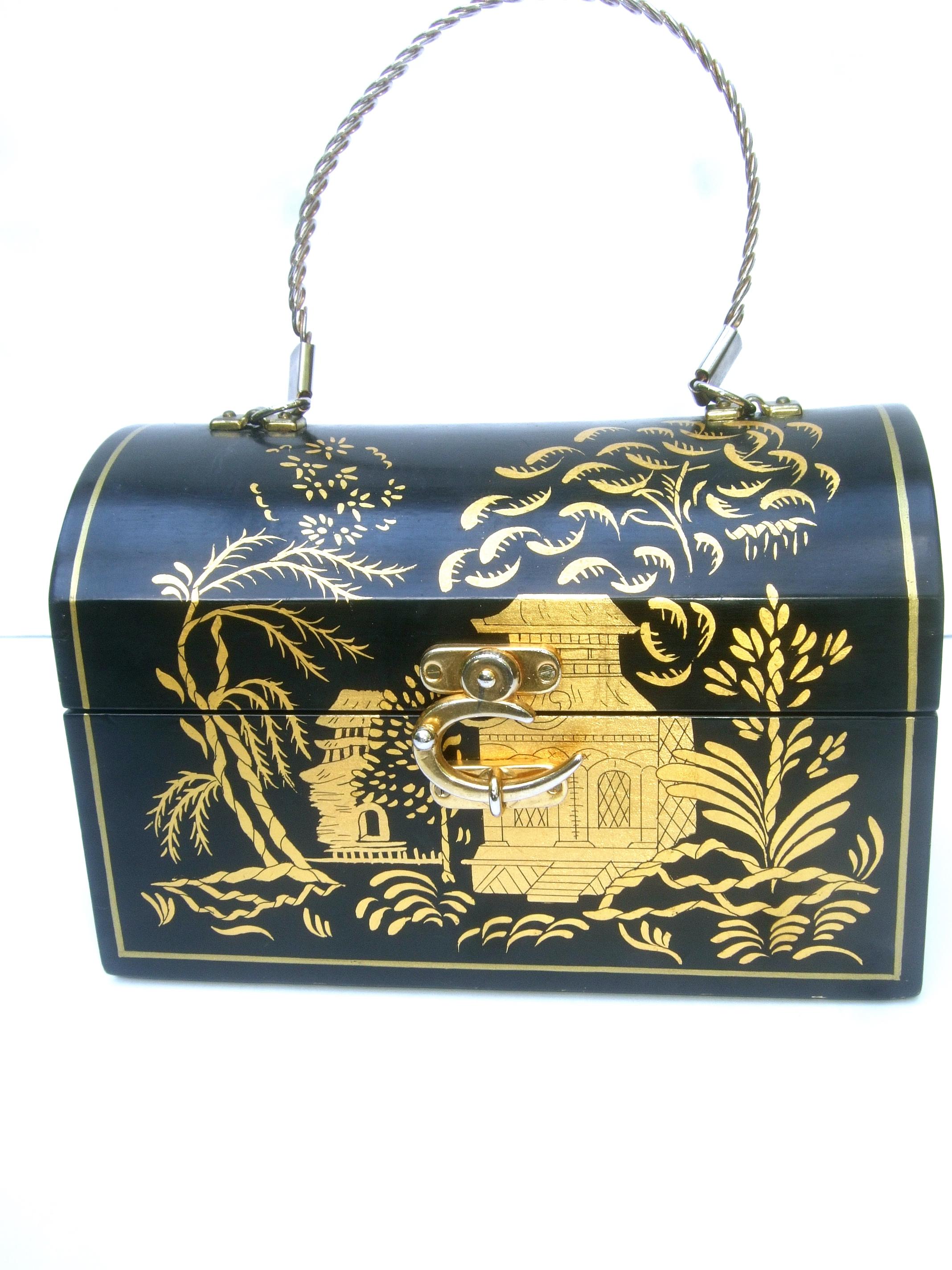 1970s Chinoiserie black & gold handpainted wood trunk box purse

The unique wood artisan box purse is embellished with a lush scene of exotic foliage & pagoda structures; illuminated against a black enamel background

Adorned with a sleek gilt metal