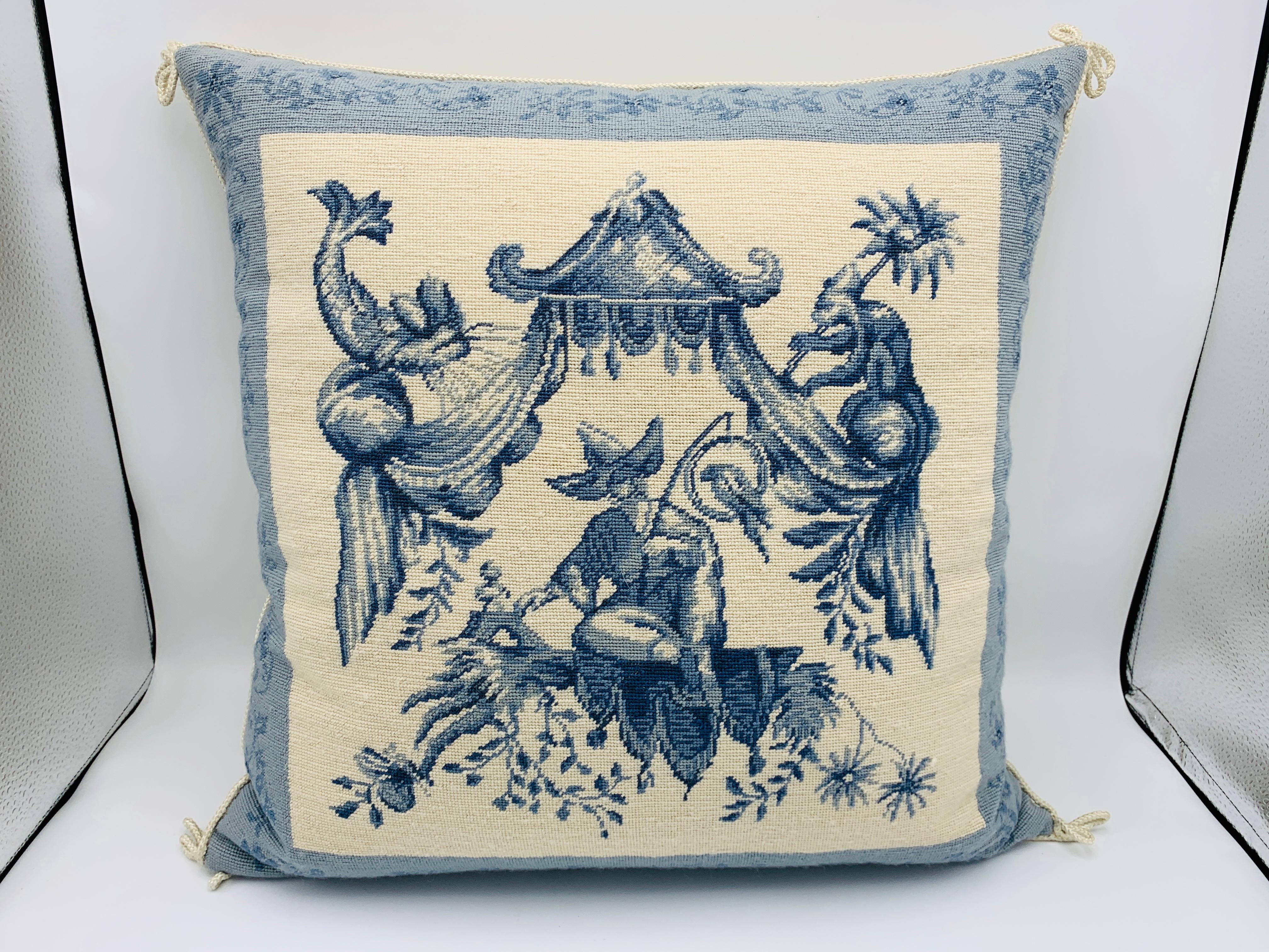 Listed is a stunning, 1970s blue and white chinoiserie needlepoint pillow. Tight-knit needlepoint weave along the front side, with a beige cotton-velvet backing, complimented by an ivory colored rope-ribbon welt. Zipper closure. Includes down insert.