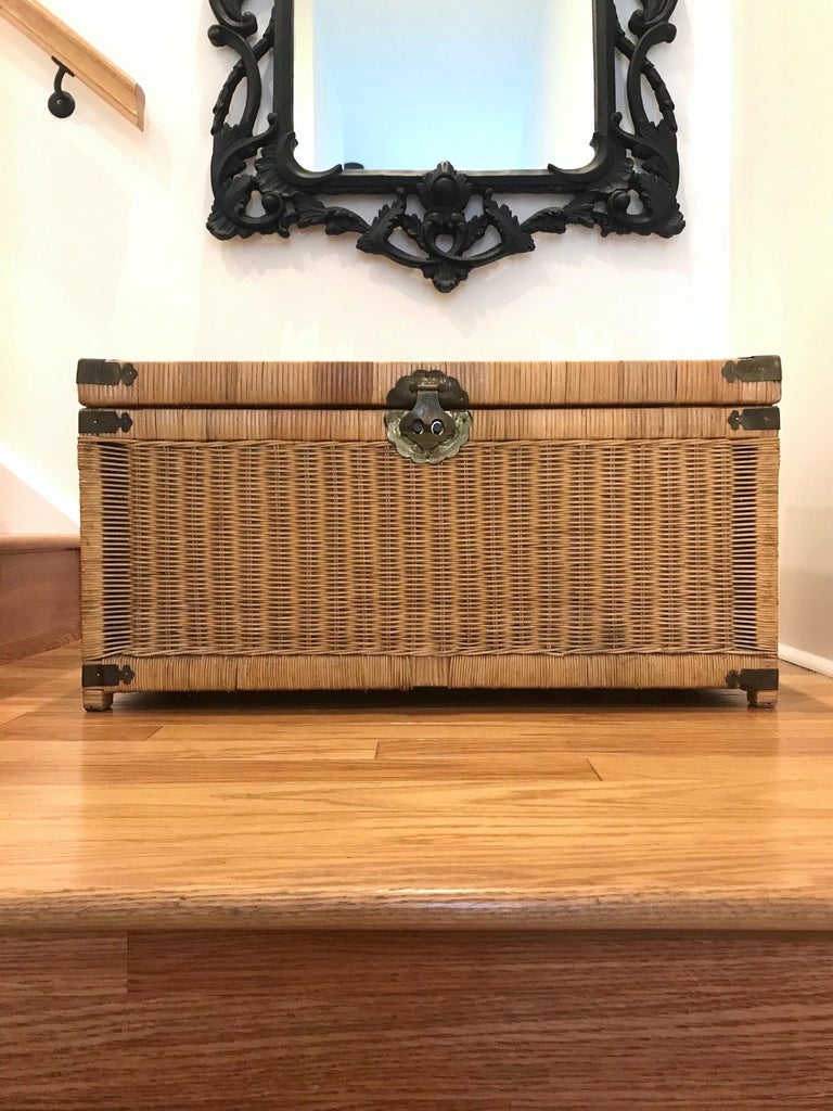 Vintage Asian storage chest and trunk in natural handwoven wicker. Campaign style design featuring a wood frame wrapped in woven wicker with brass metal hardware. Hammered brass metal accents and hardware with Asian motifs throughout. Lid opens to