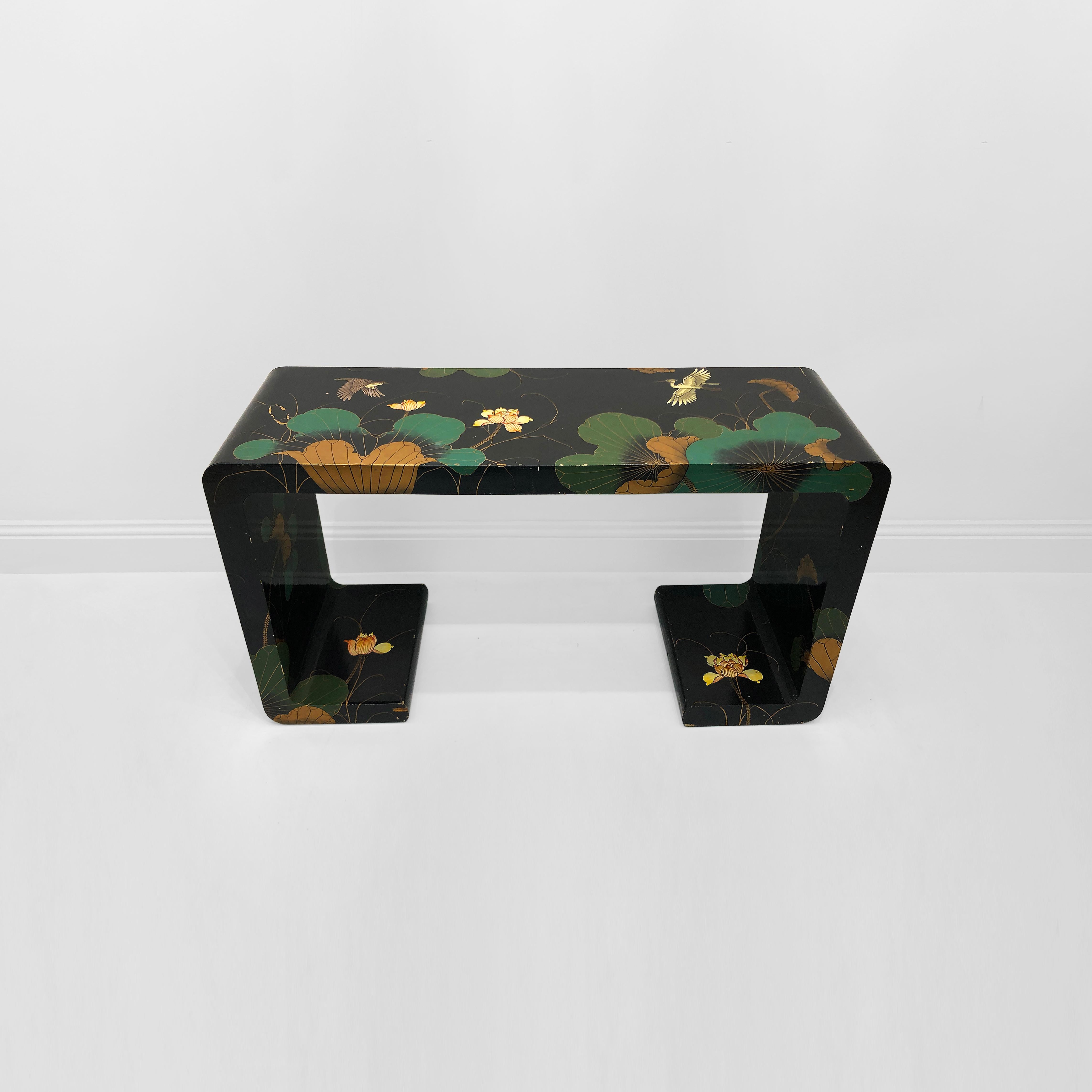 This 1970s Chinoiserie waterfall console table is a remarkable piece of furniture that exudes a blend of elegance and exotic charm. The console table has a sleek organic shape with waterfall sides and base. The black background has a striking