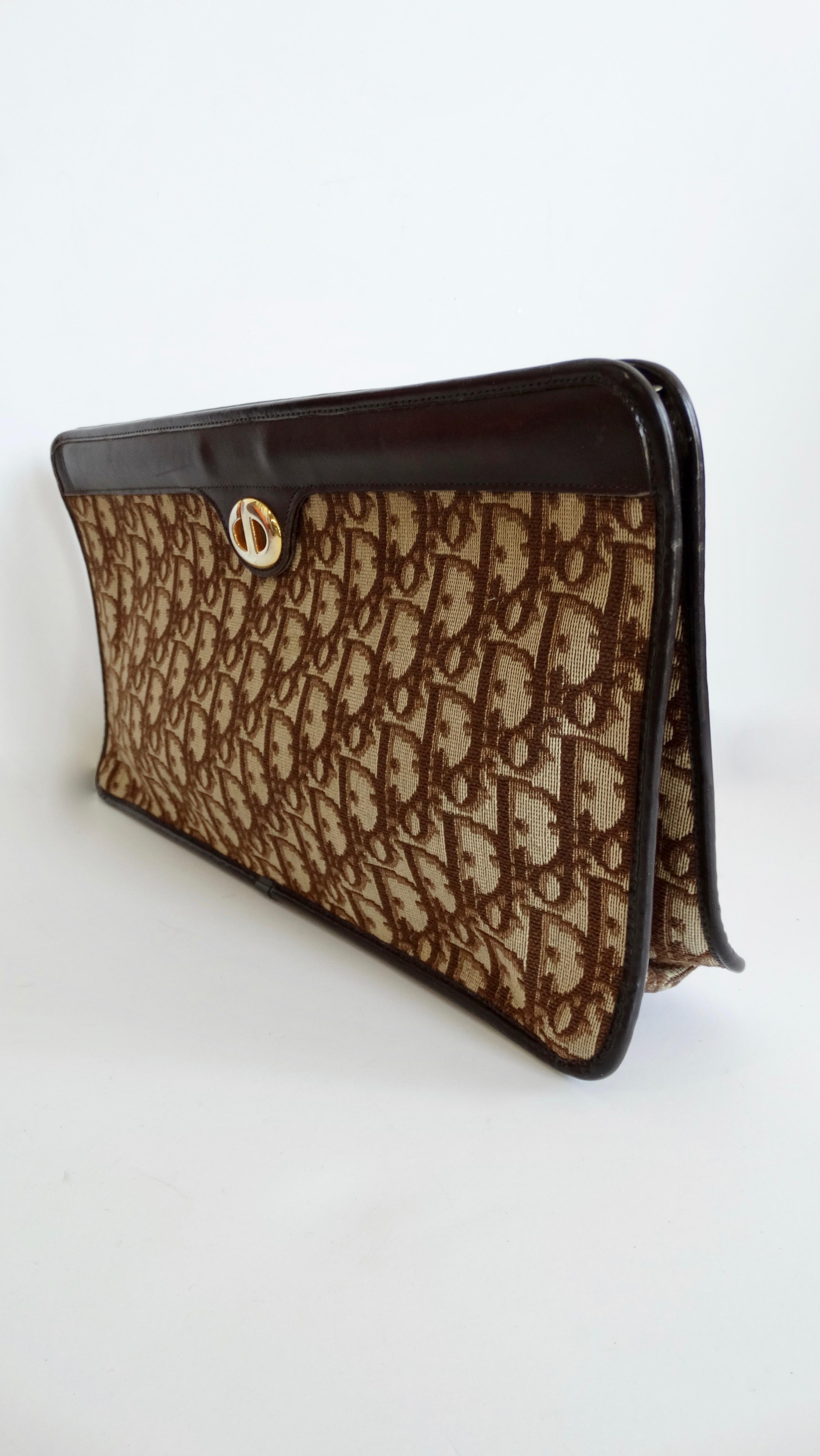Complete your bag collection with this monogram Dior gem! Circa 1970s, this jacquard canvas clutch features the iconic Dior monogram in brown and beige, brown leather trim and the Christian Dior initials emblem in gold hardware on the front face.