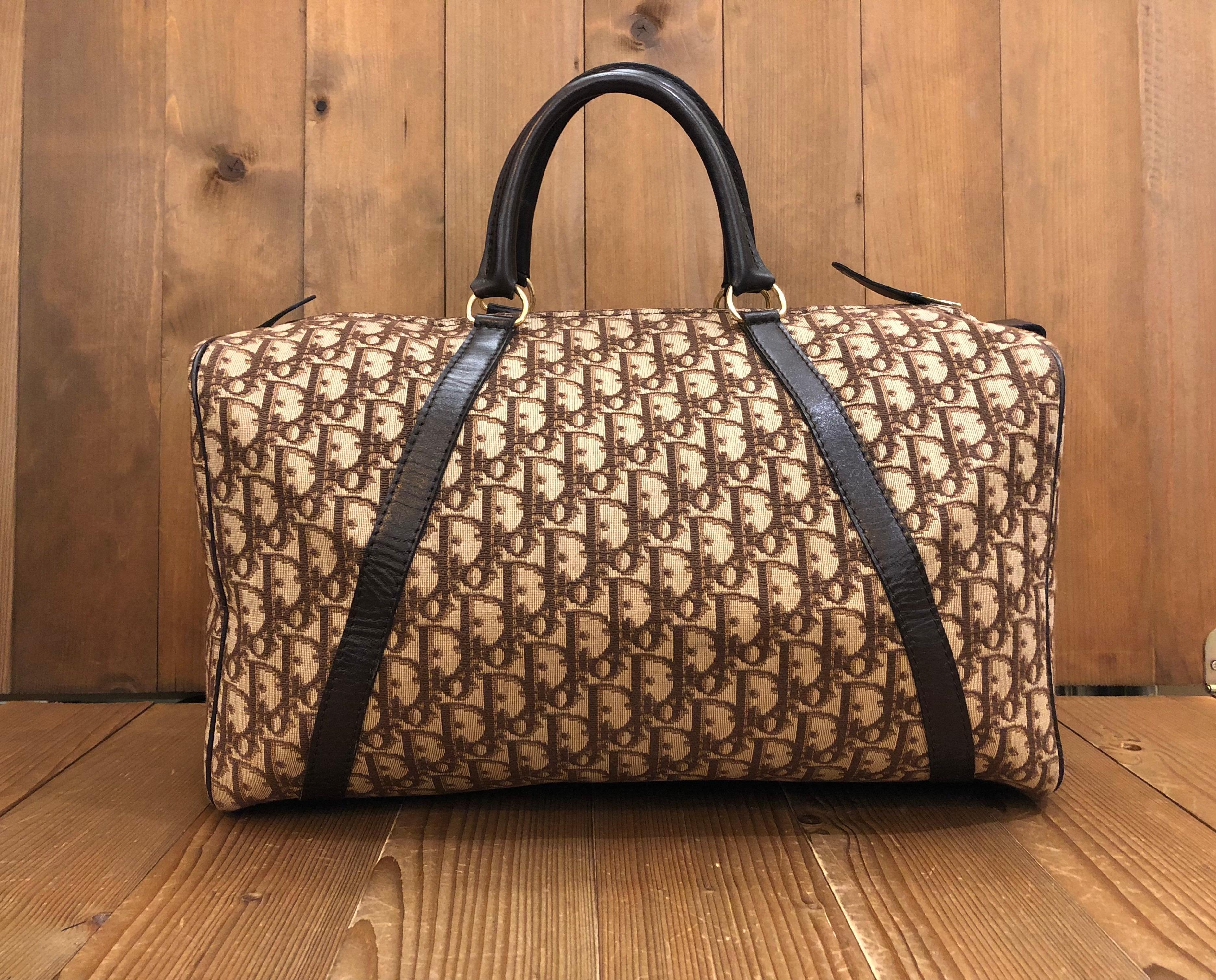 This vintage CHRISTIAN DIOR boston bag is crafted of iconic Dior Trotter jacquard and leather in brown. Top zipper closure opens to a coated interior in brown featuring a zippered pocket. Made in France. Measures approximately 15.5 x 8.5 x 9.5