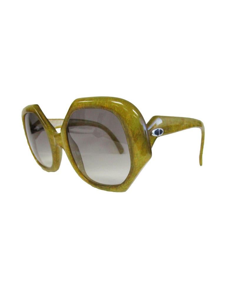 

An iconic pair  of vintage Marc Bohan for Dior sunglasses!

These green sunglasses feature a structured oversized lens and silver branding on the arms!
The color way is really interesting because you can see a plethora of different shapes from the