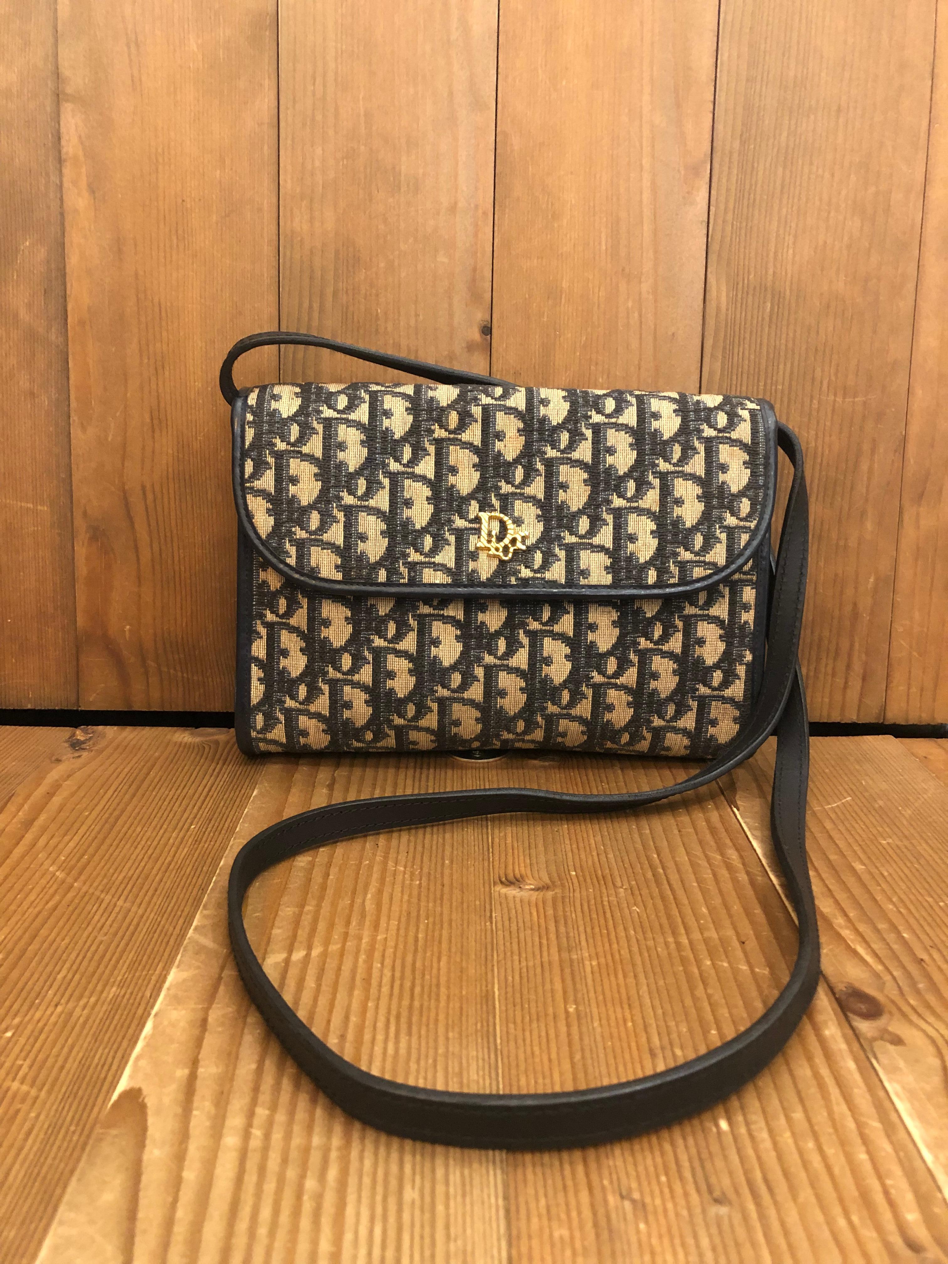 1970s Christian Dior 2-way crossbody clutch bag in navy trotter jacquard and leather featuring an interior zip pocket. It can be carried as a clutch or a crossbody bag by securing the detachable leather strap with snap fastenings. Made in France.