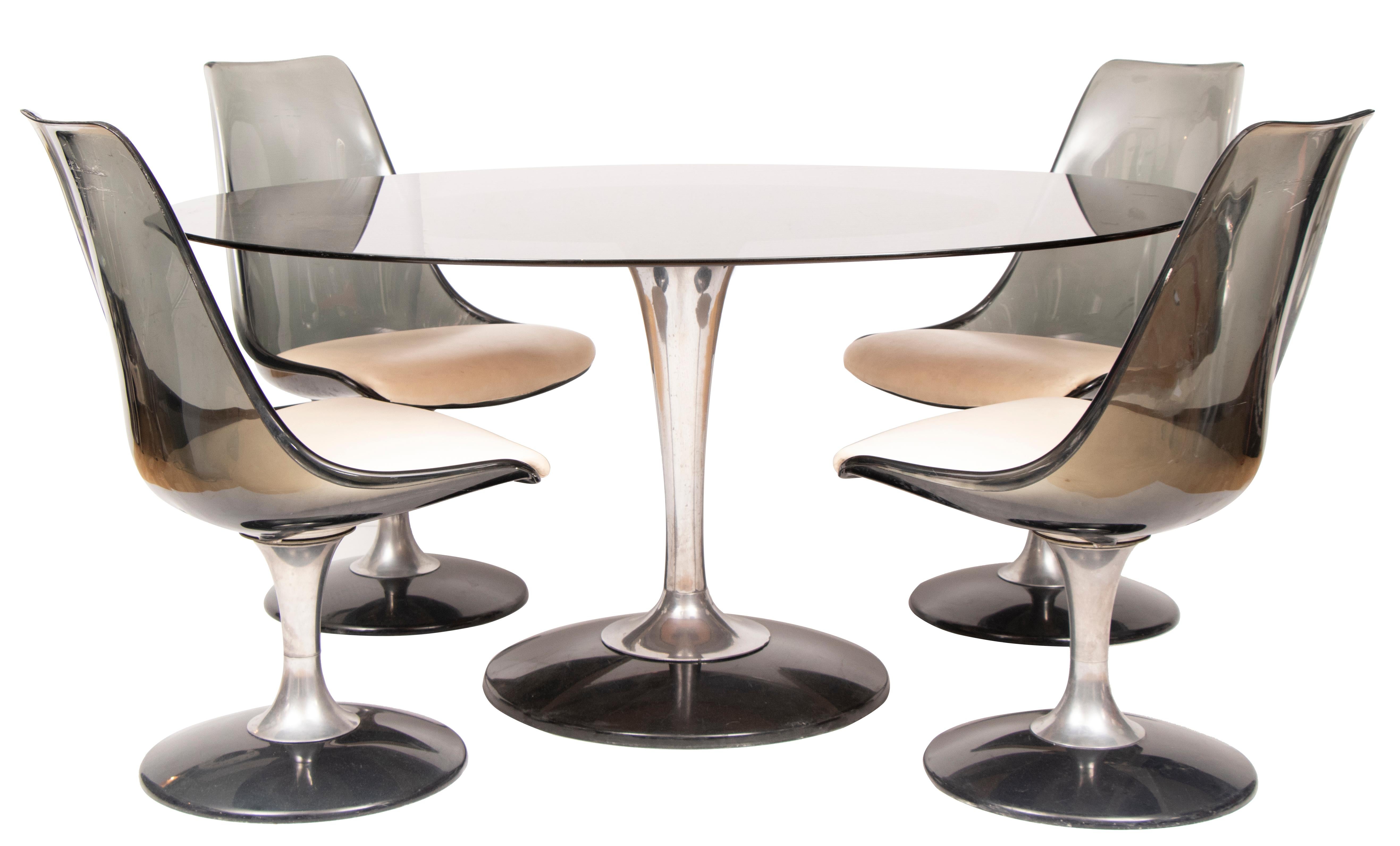 1970s chomcraft dining room set with an oval table top and four matching swivel tulip chairs. The tulip table has a thick smoked glass top, aluminium stem and smoked lucite base. The formed, organic-shaped, smoky, lucite chairs match the base with