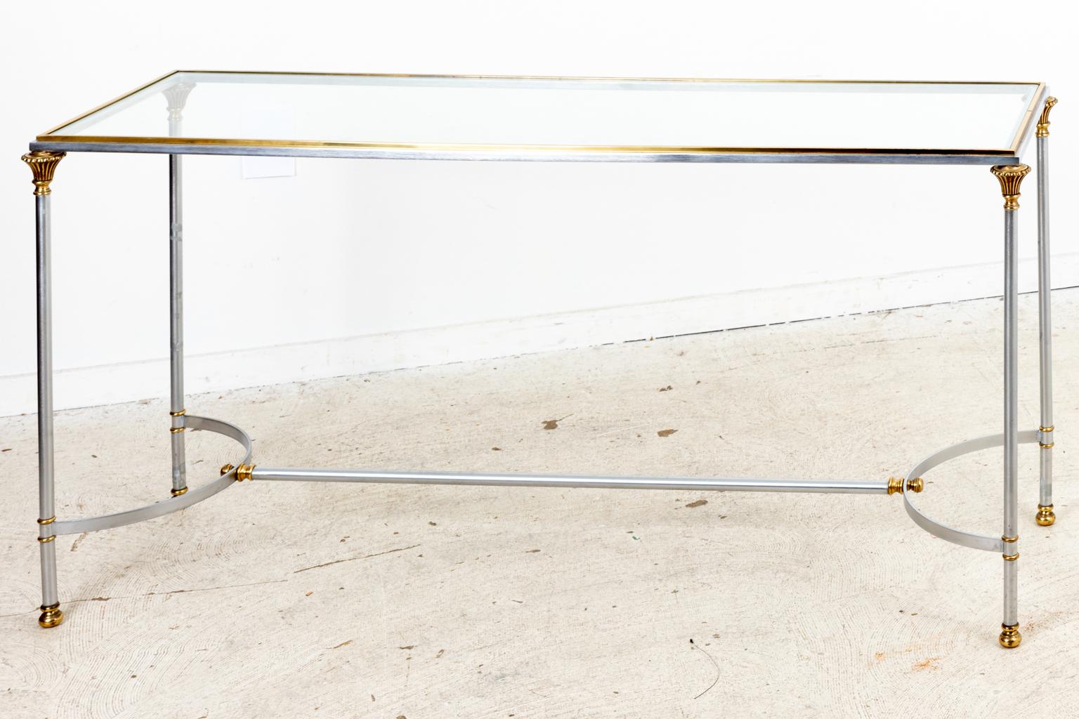 Circa 1970s Mid-Century Modern style Italian Chrome and Brass console table with a glass top made for Bloomingdales. The table features a bottom stretcher. Made in Italy. Please note of wear consistent with age including oxidation and patina.