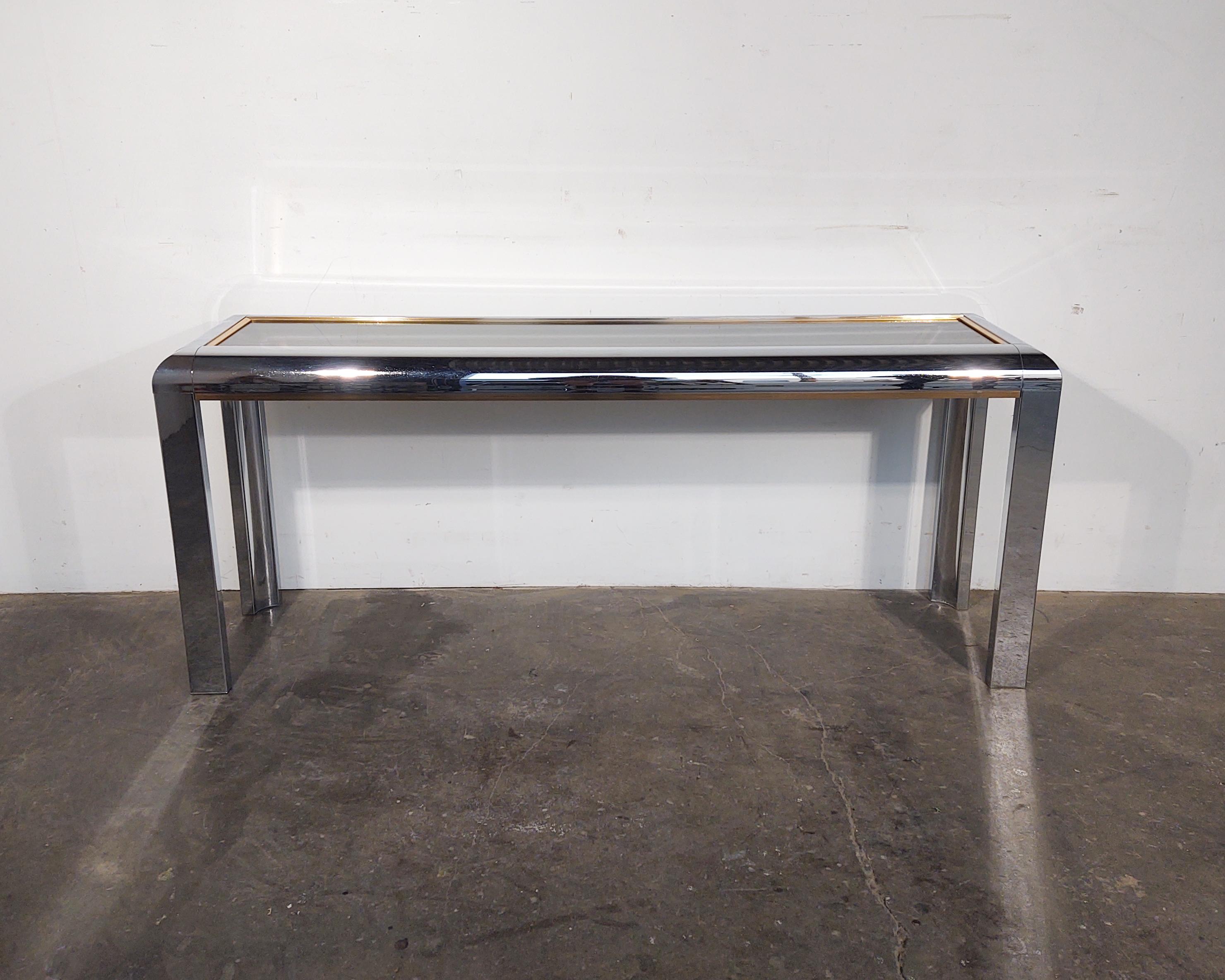 Minimal console / media table with chrome frame and casters circa 1970s designed by Milo Baughman. Thick glass top and lower shelf. Glass is removable.