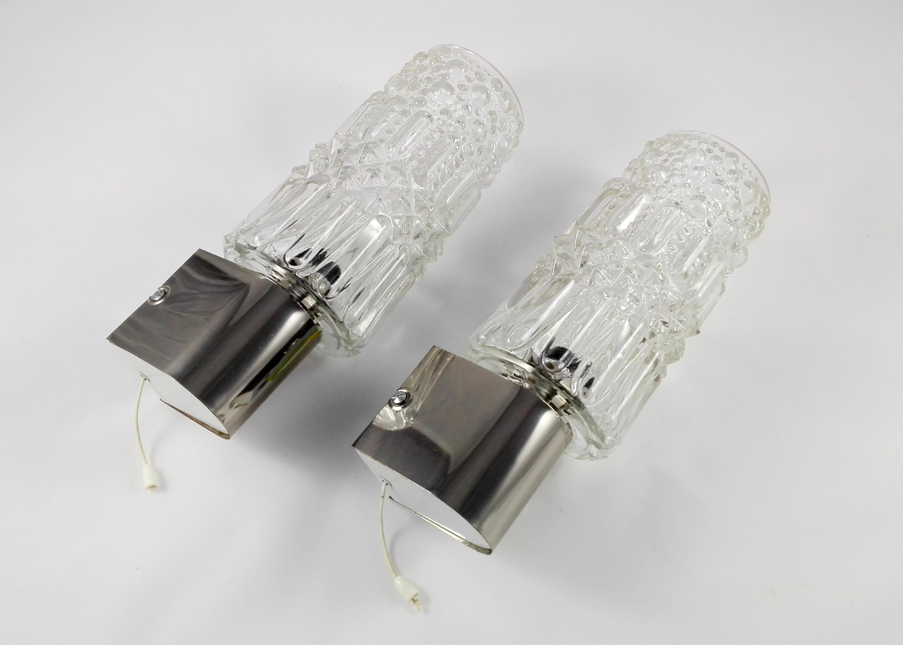 A pair of 1970s wall lamps. Faceted clear thick crystal shades, chrome frames. Thanks to their size and shape, these sconces are perfectly fitting for a bathroom, bedroom or small study. The lamps are directly lightened with a wire