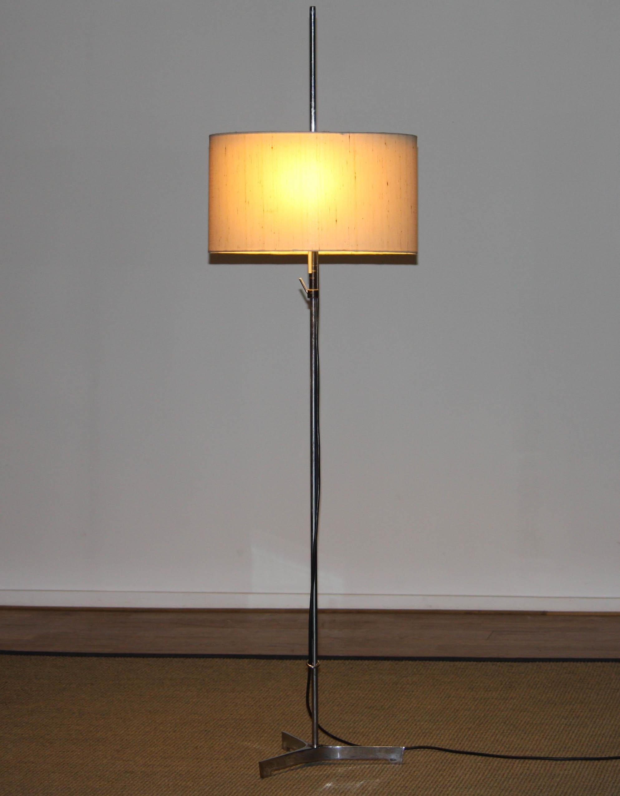 Extremely beautiful 'Modernist' floor lamp on a great designed three legged base all in chrome. The original grass-cloth shade is adjustable in height. Two E 27 / E 28 fittings and technically in perfect condition. the cord-switch has the option to