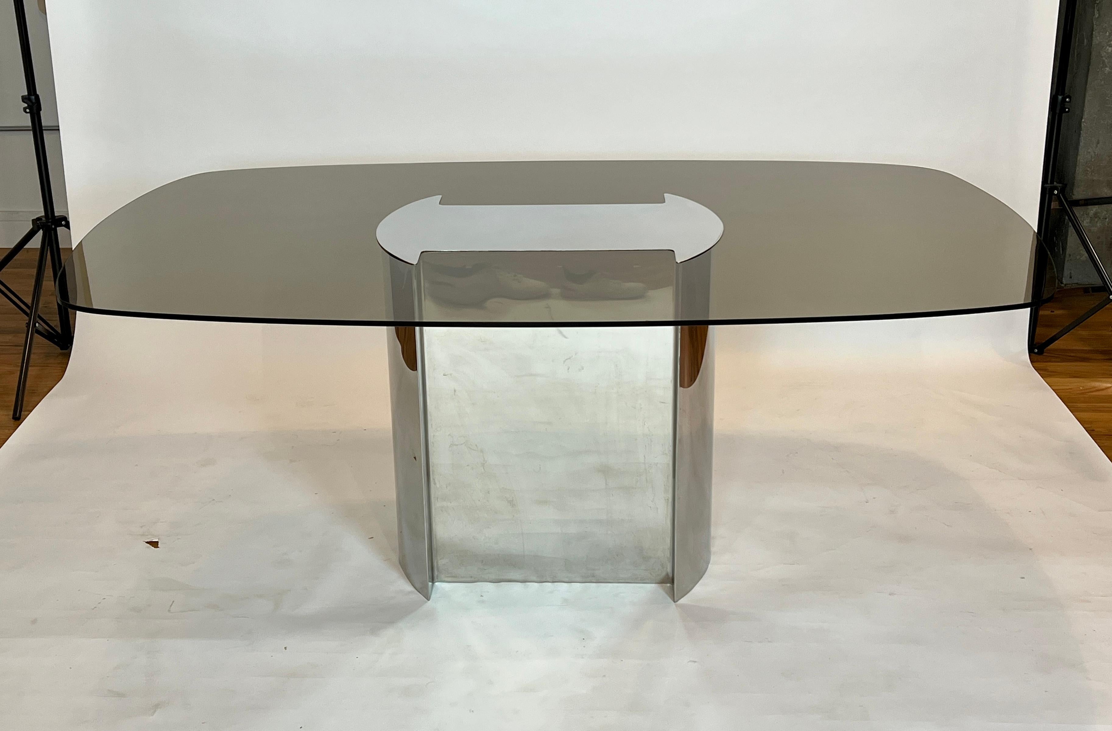 1970's dining table made of polished chrome base and runner top with smoked glass. The chrome top caps the glass affixing it to the base. This table was paired with the set of Willy Rizzo dining chairs pictured in the listing but we do not have a