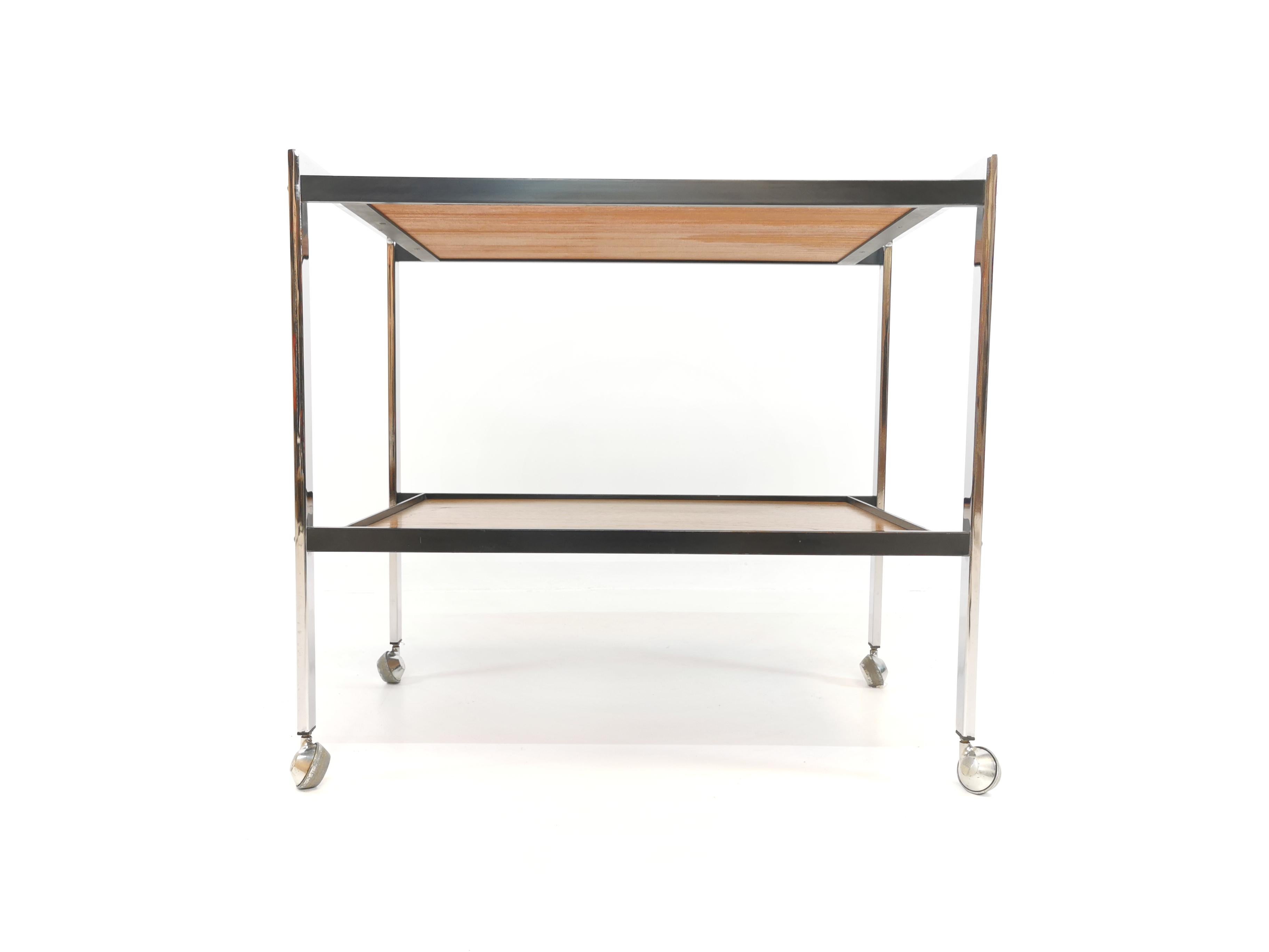 A drinks trolley by Howard Miller. A superb piece of 1970s high-end design. 

Chrome frame and beautifully grained teak tiers. Sat on metal casters.