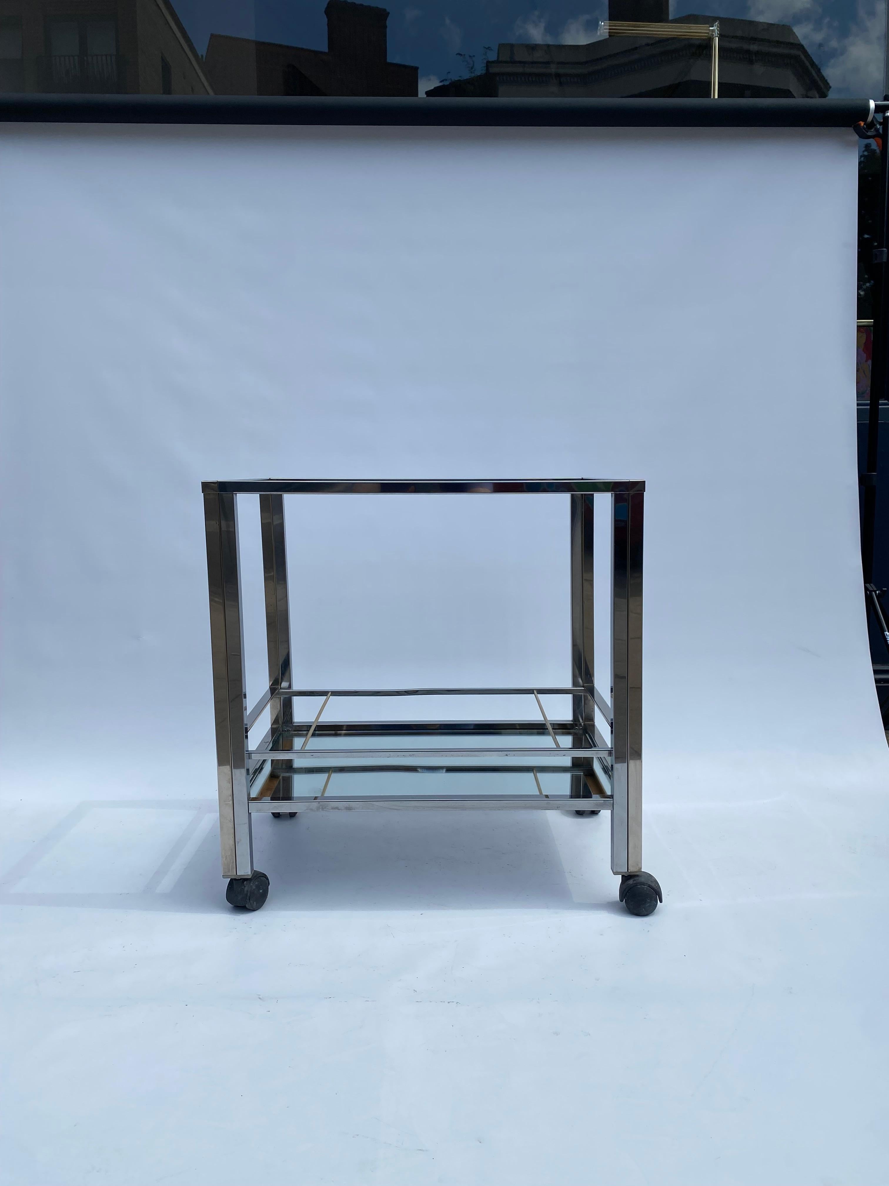 A stylish vintage 1970s bar cart in the manner of Renato Zevi and Romeo Rega.

The two tone chrome frame supports two tieres of framed glass and mirror panels with cases for the bottles and bar accessories.

The frame is overall in decent condition,