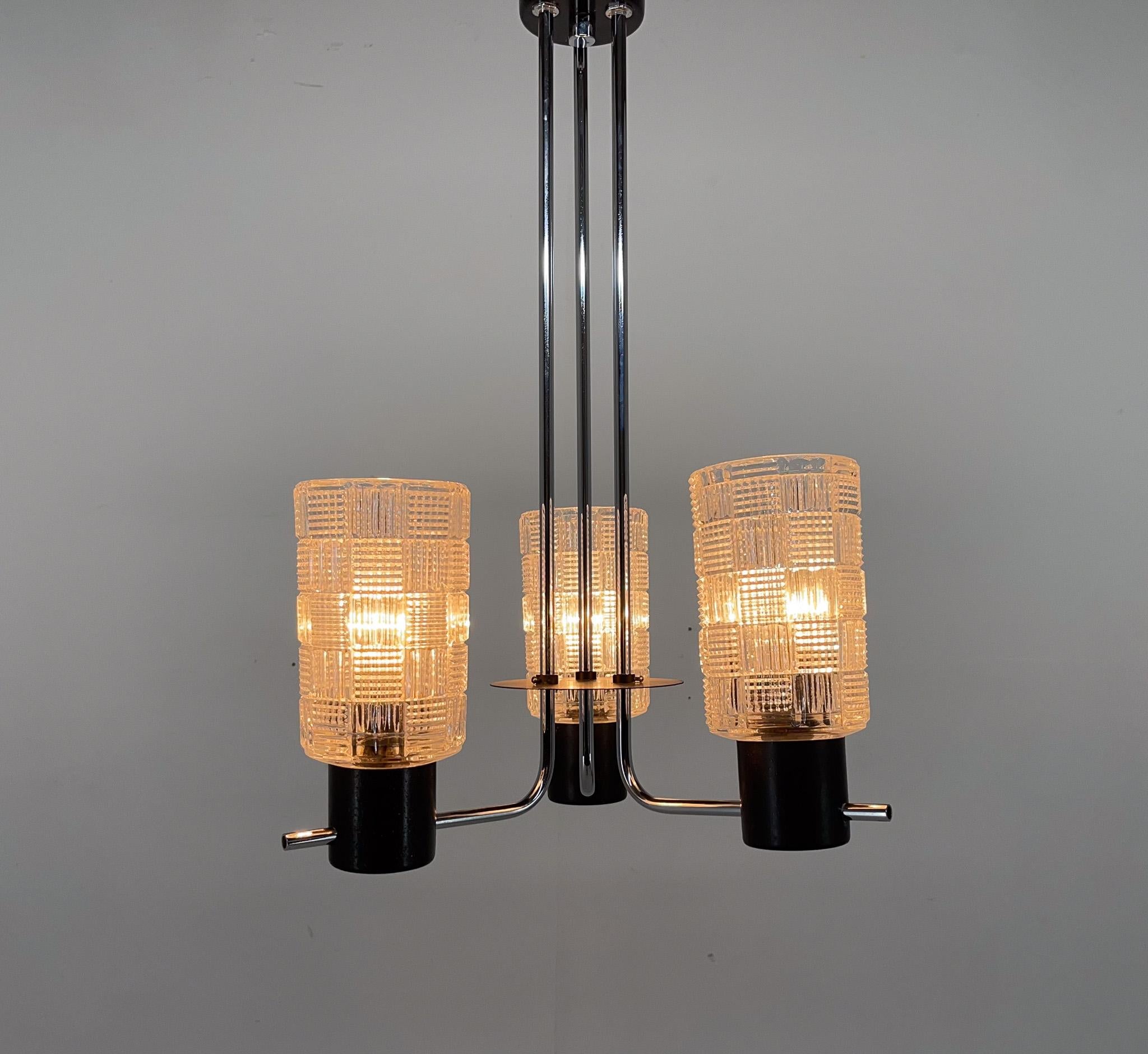 Vintage chandelier made of chrome, metal and three clear glass shades. Produced in former Czechoslovakia in the 1970's. 
Bulbs: 3x 1 E26-27. US wiring compatible.