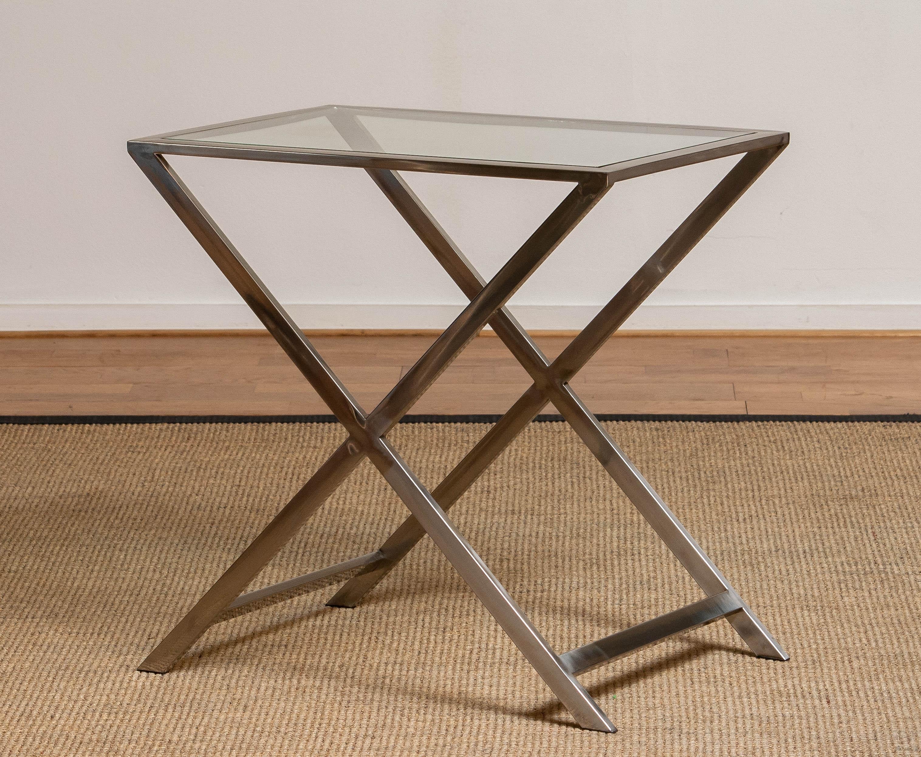 Cross legs site table with glass top in chromed metal and in the style of Milo Baughman. Beautiful welded and in overall good condition.