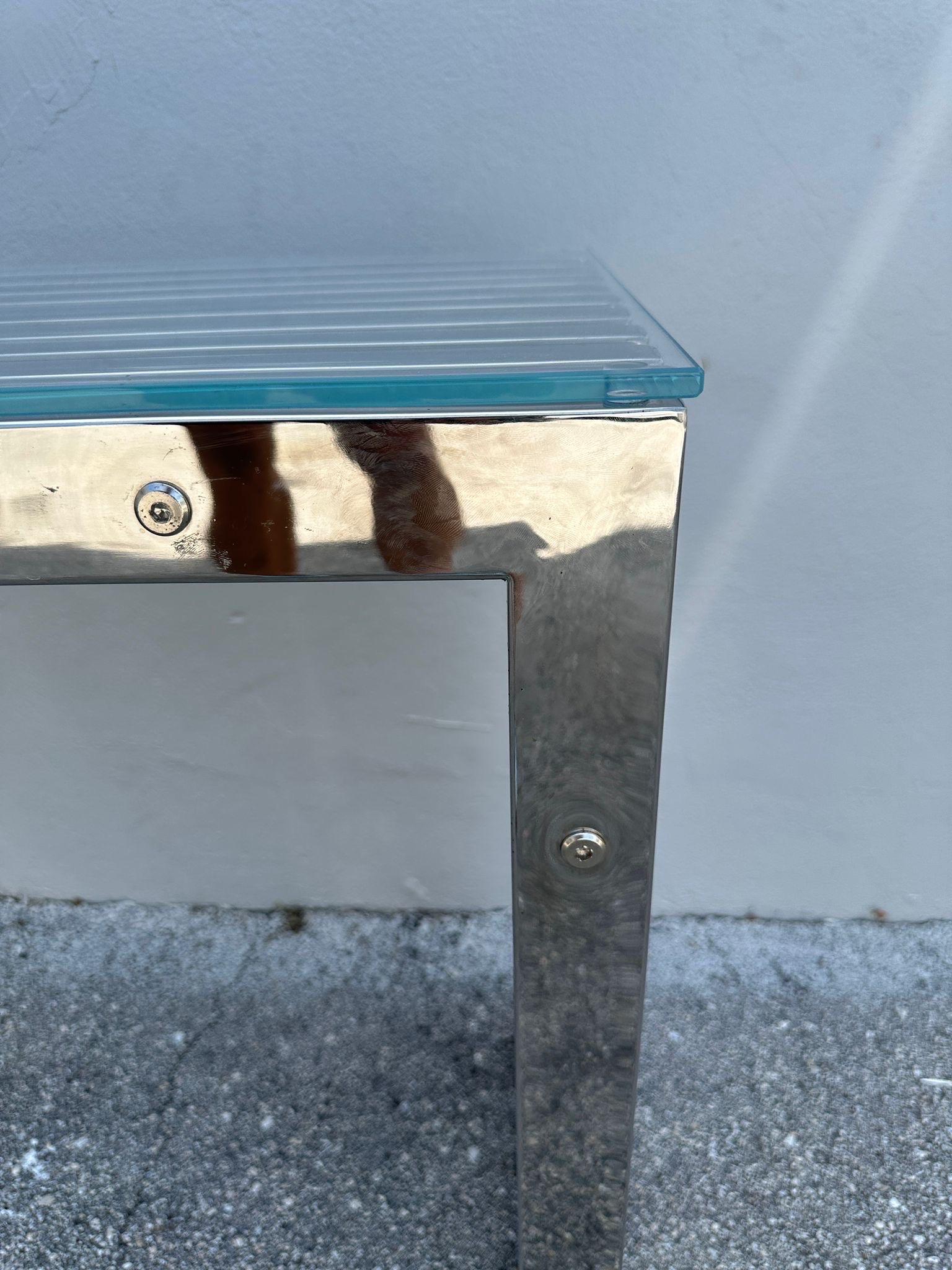 This multi-slat chromed console table with custom glass top in the style of Milo Baughman is perfect for behind a sofa or foyer/ entry table.  Distinct accents and very solid.  Extremely stylish console.