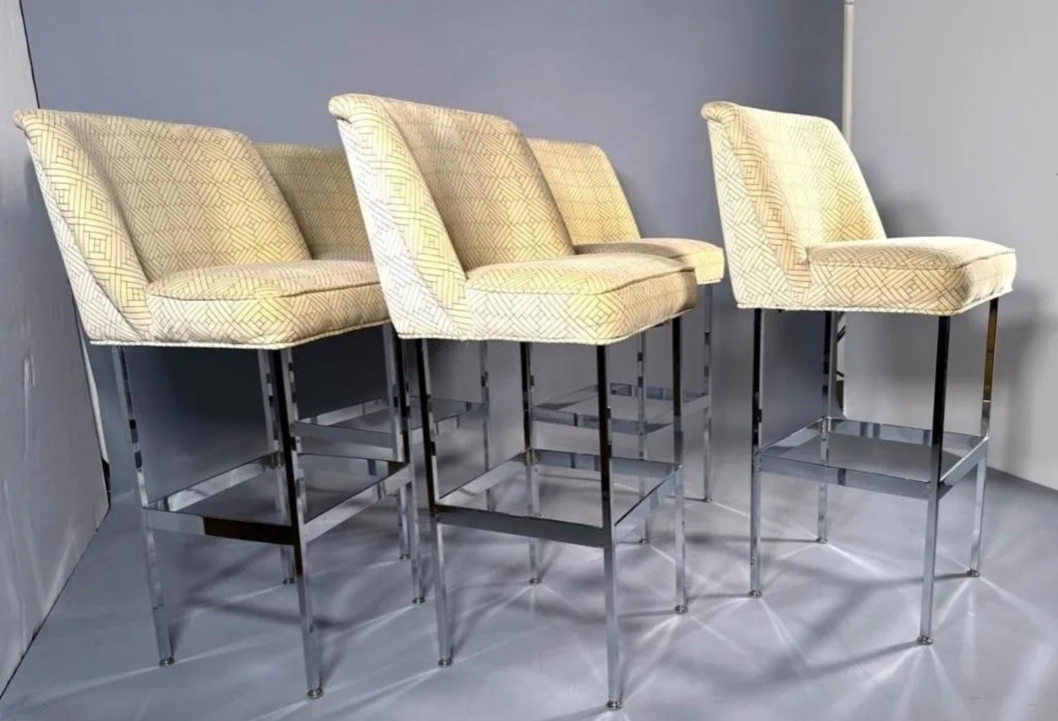 Set of five (5) chromed steel and velvet bar stools, 1970s. The seats and backs are fully upholstered in printed velvet with self-welt details; the squared chromed steel legs are joined by stretchers with foot rests. 