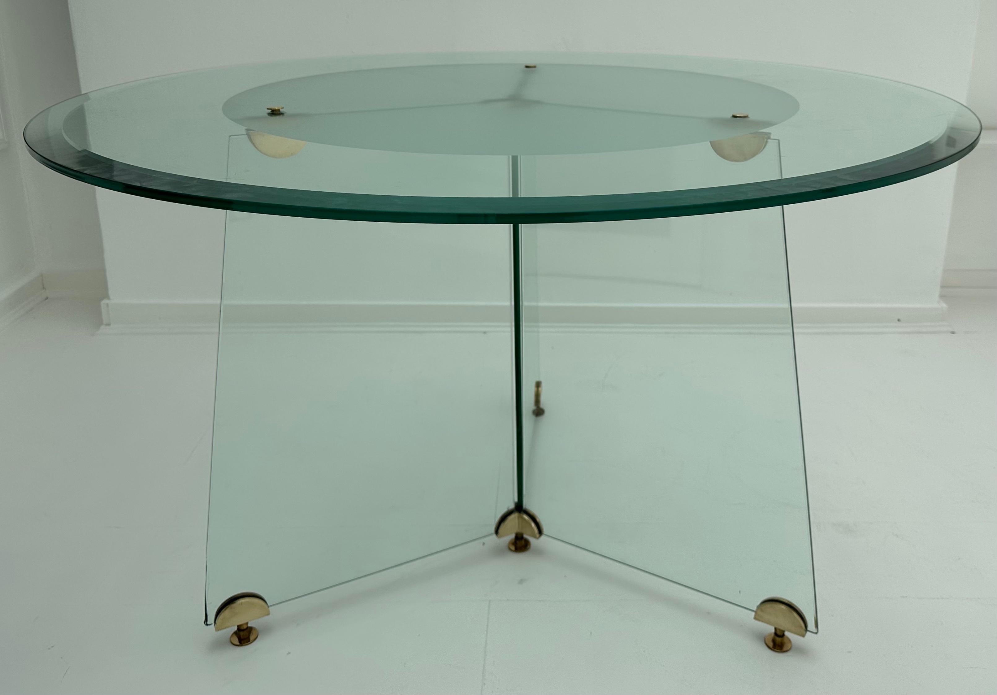 1970s American bevelled & frosted glass circular dining table with feature brass fittings in the style of designer Leon Rosen for Pace Collection.  This three-legged table is made entirely from glass with brass fittings and feet.  The edge of the