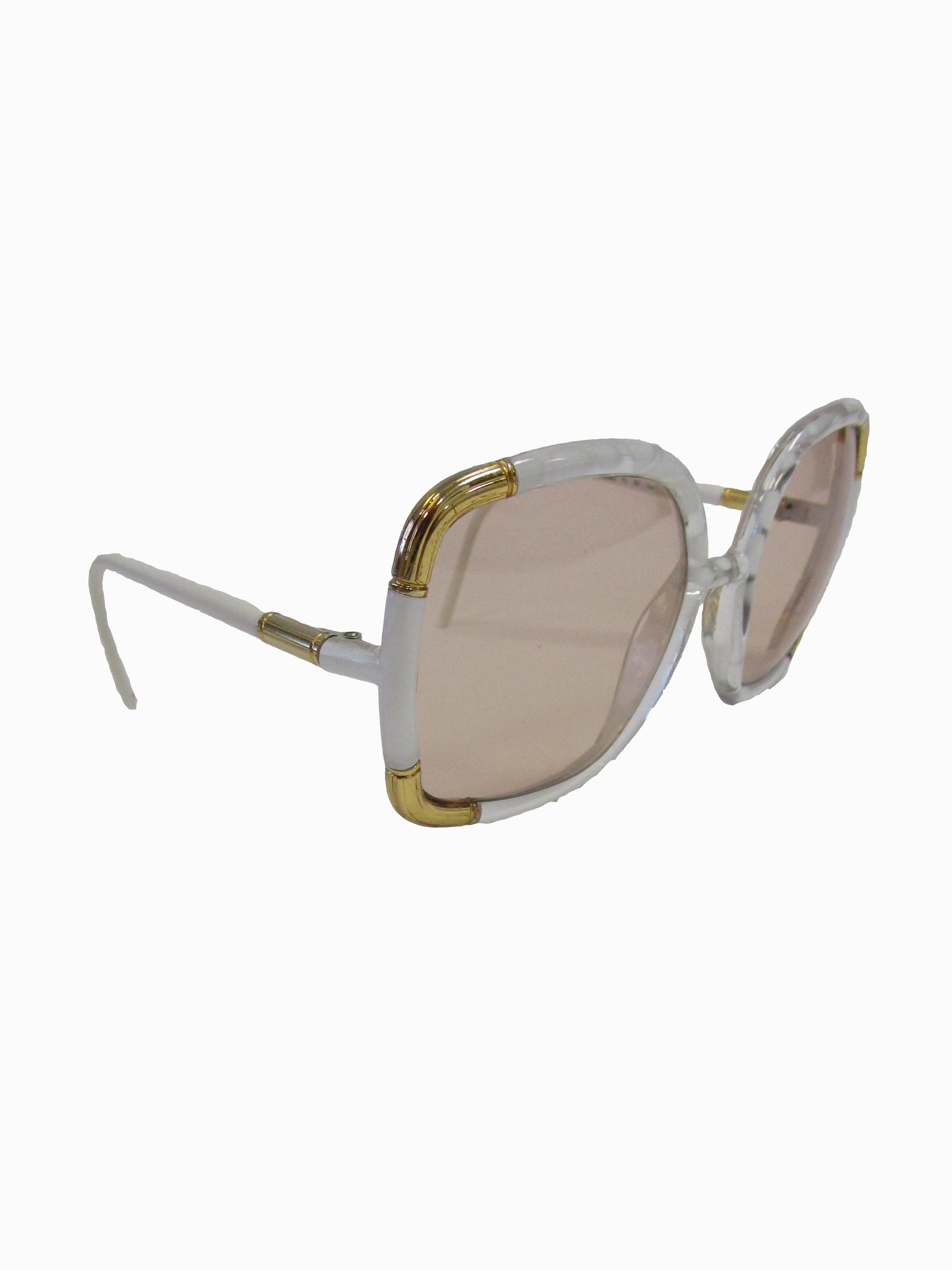 Classic Ted Lapidus Paris sunglasses done in white marbled acrylic with gold hardware. Grey lenses are oversized.

Lens Width-57mm
Bridge Width- 15mm
Temple (arm) Length - 5in