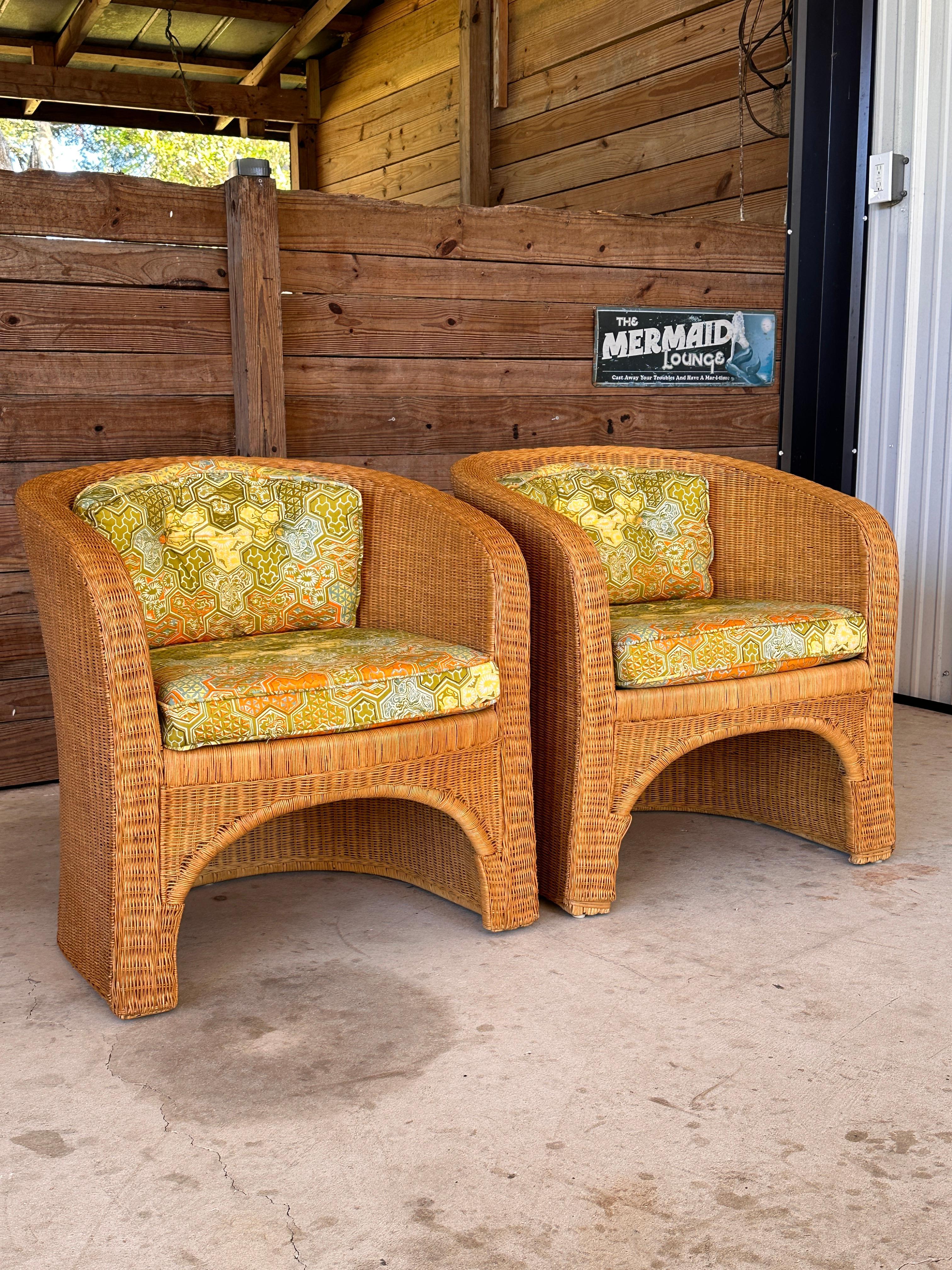Pair of Vintage 1970s Rattan Wicker Tub Chairs by Ficks Reed.
These chairs feature a graceful curved design with tightly woven rattan and the original vibrant geometric-patterned fabric. The wicker is in excellent condition, with minor fading