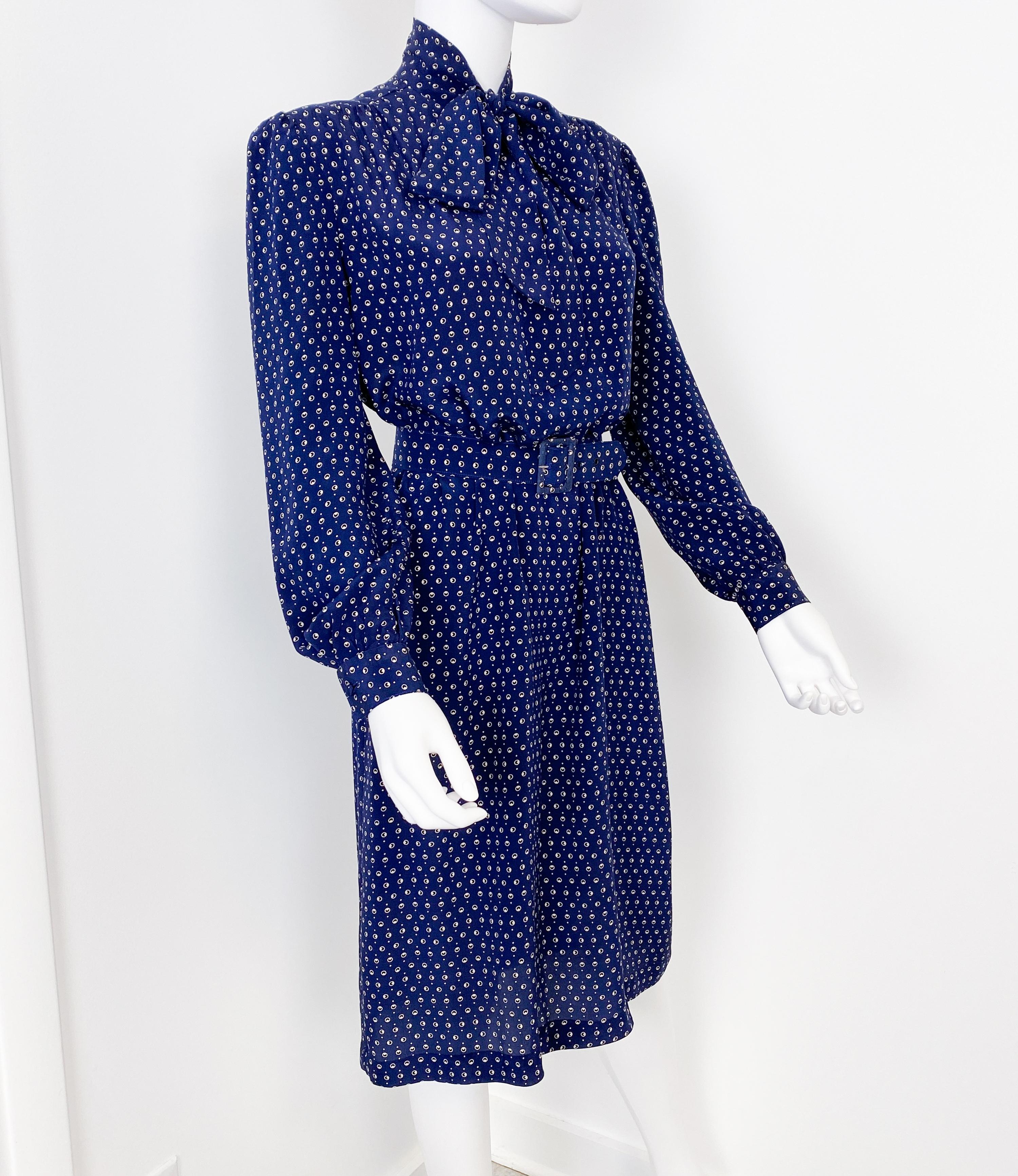 Dieses exquisite Cocktailhemdkleid im Vintage-Stil der 1970er Jahre verkörpert mit seiner schlanken, geradlinigen Silhouette und dem raffinierten Schleifen-Kragen mühelose Raffinesse. Aus luxuriöser kobaltblauer Seide gefertigt und mit charmanten