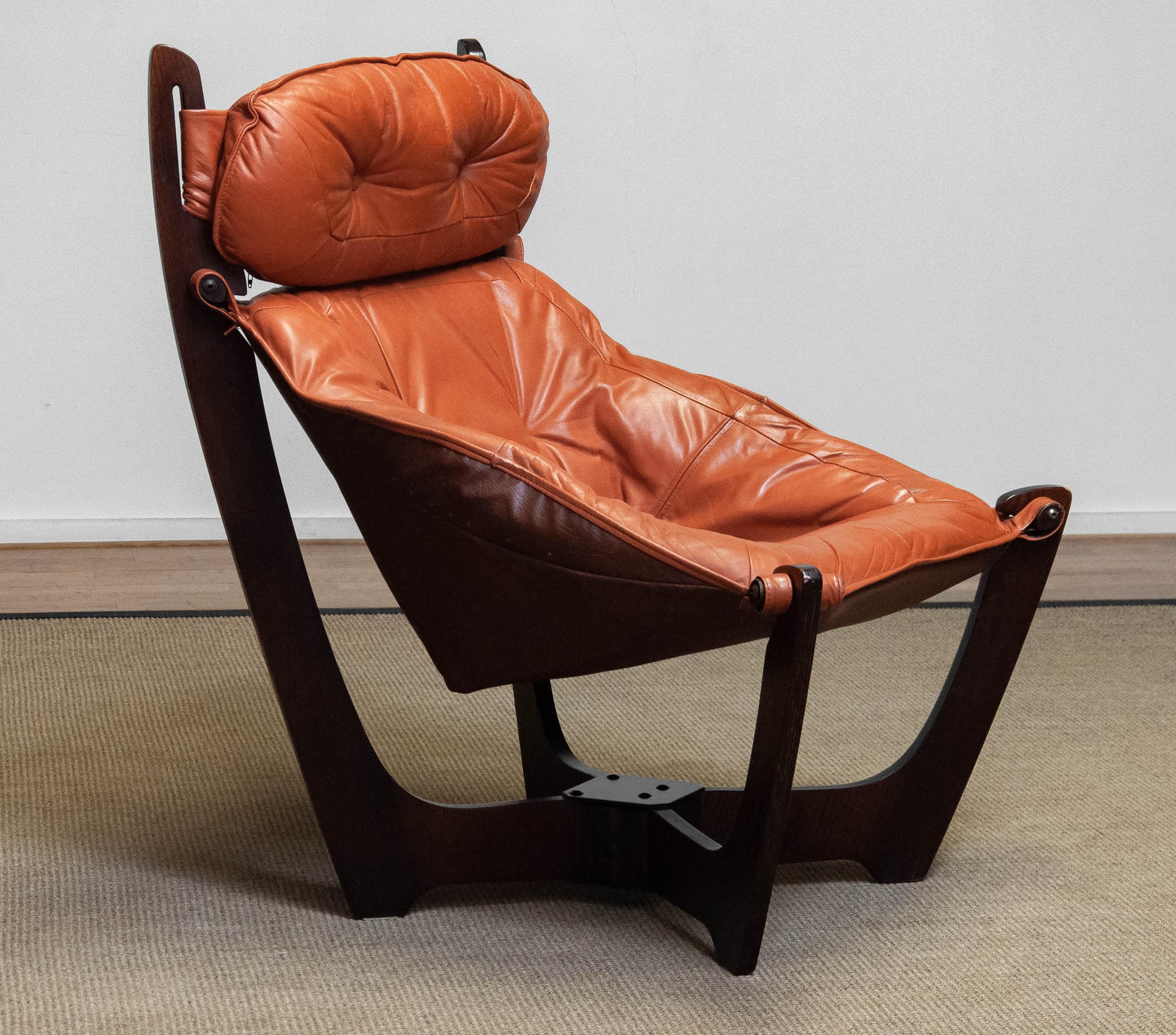 Beautiful and very comfortable model: 'Luna' armchair by Odd Knutsen for Hjellegjerde in Norway. 
The chair is upholstered with cognac colored leather and hangs in a dark brown beech laminated frame.
This chair is in overall good condition.