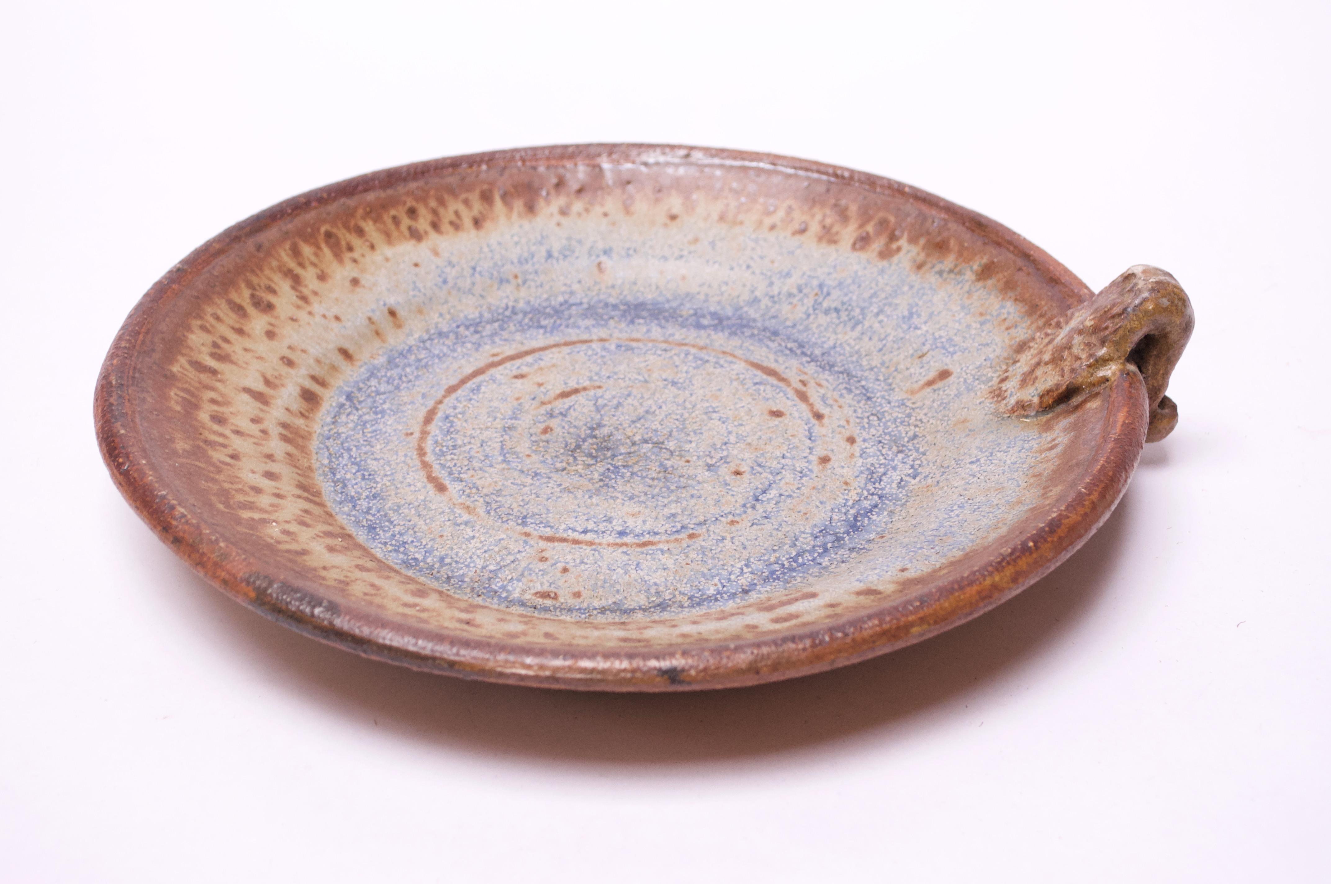 Attractive stoneware charger / decorative plate in blue and brown with concentric circles pattern (inner circle is only a partial outline by design). Additionally, the mottled edge and decorative handle add interesting textural elements to the