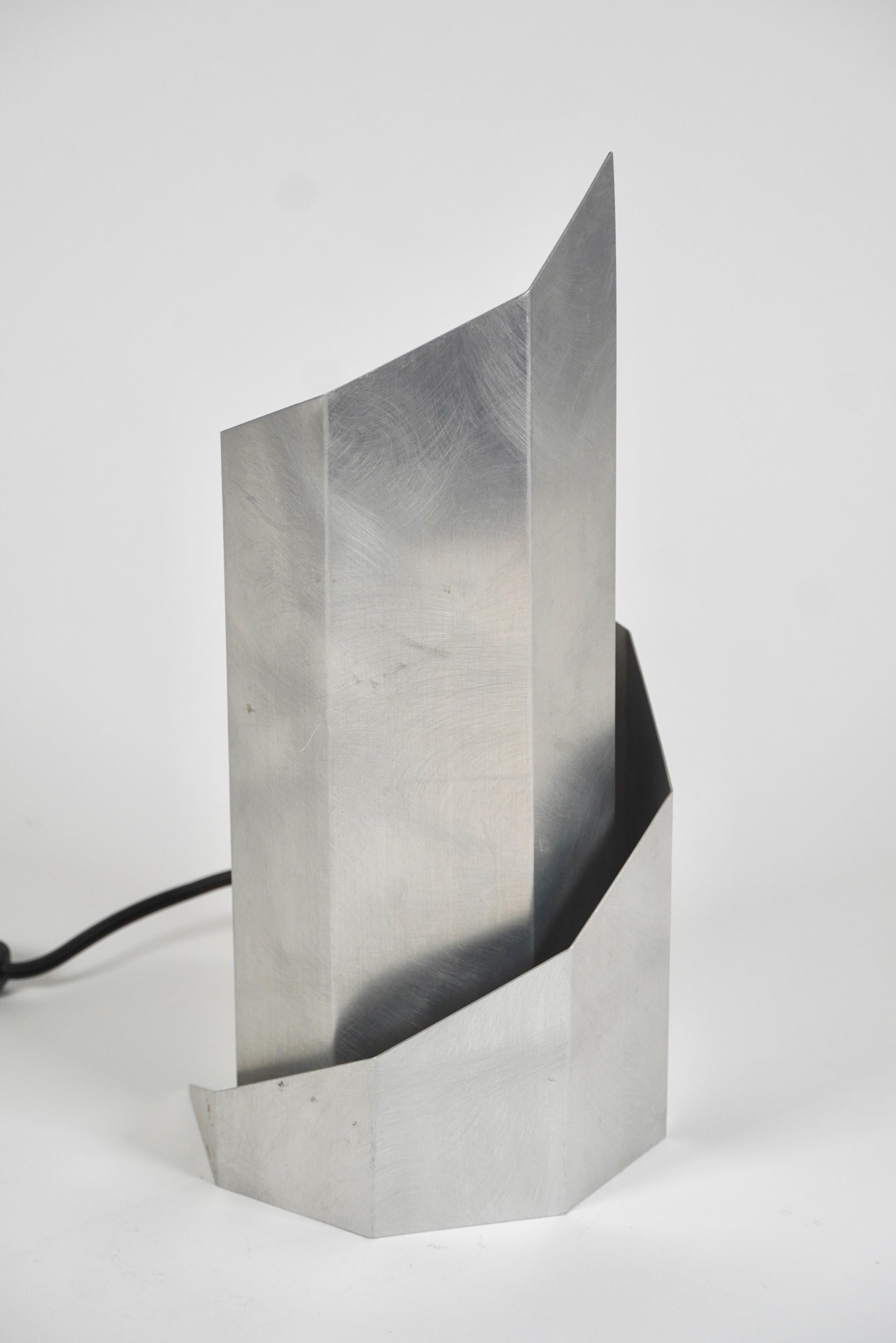 Folded aluminum table lamp by the design team of Godley-Schwan the angled folds create a spiral with both the top and base end in a point, the design casts an atmospheric light. Godley-Schwan began in 1984 when Lyn Godley and her husband, Lloyd