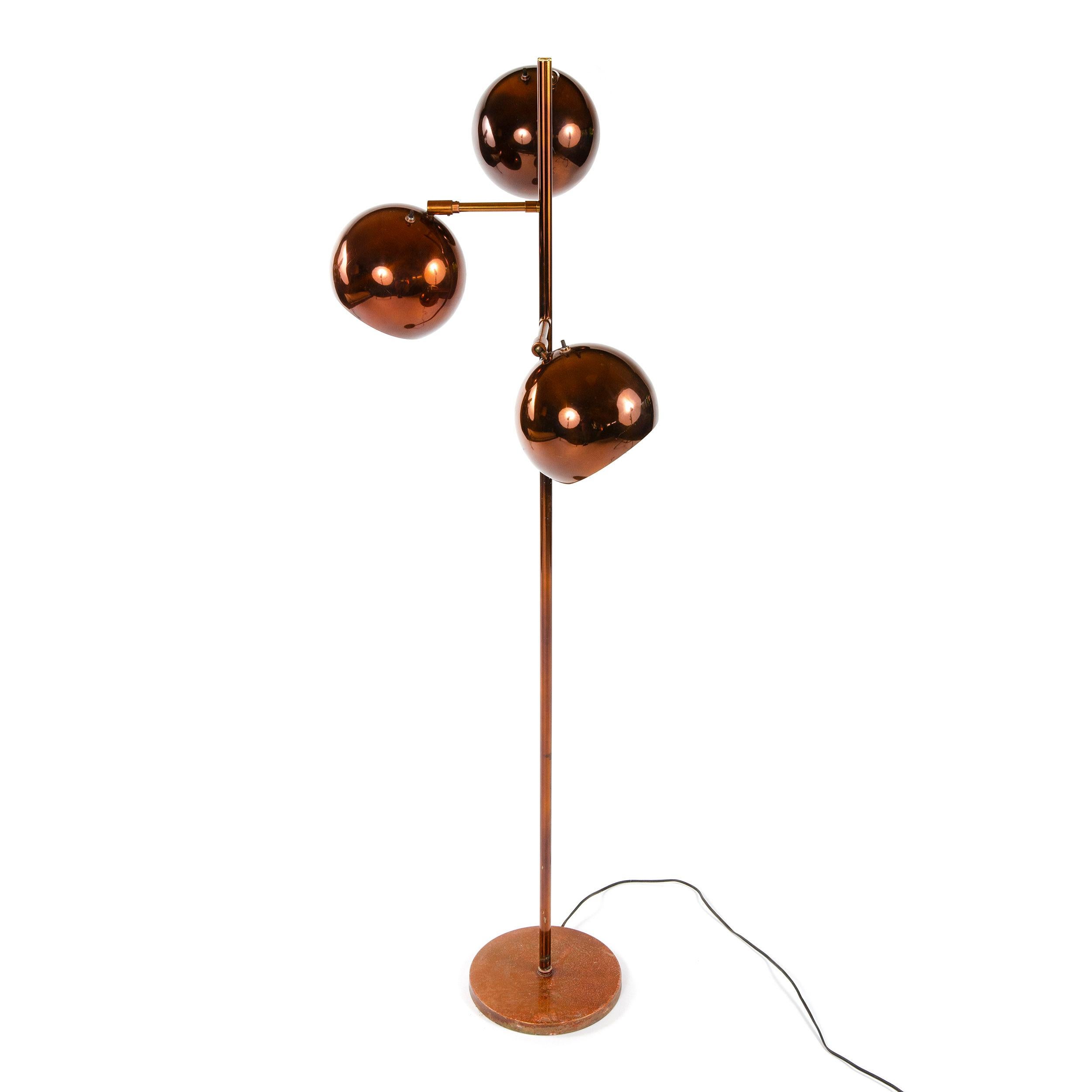 A copper floor lamp with three globular shades.