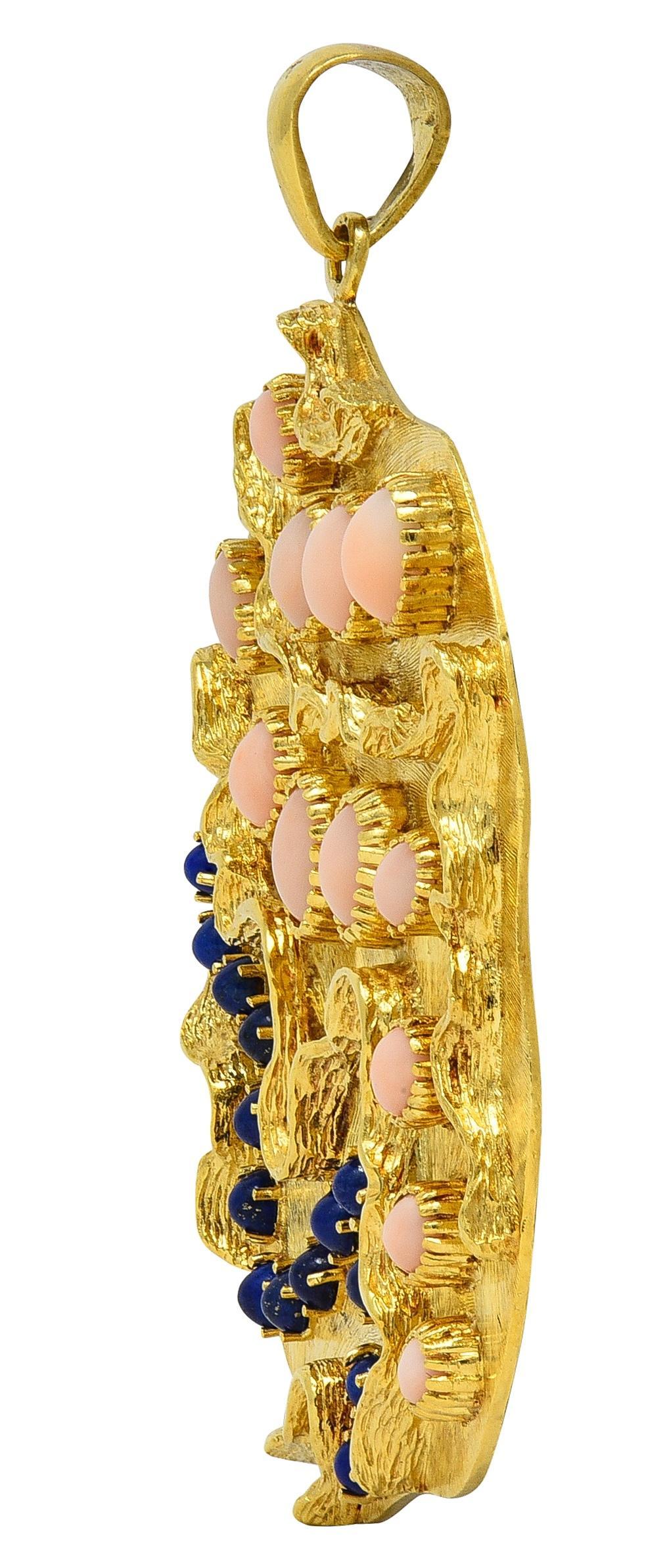 Entworfen als fast runde Scheibenform mit feiner Gravur und durchgehender linearer Textur
Akzentuiert durch erhabene verschnörkelte Motive aus Gelbgold und besetzt mit Koralle und Lapislazuli
Die Koralle wird in Form von ovalen Cabochons von 3,0 x