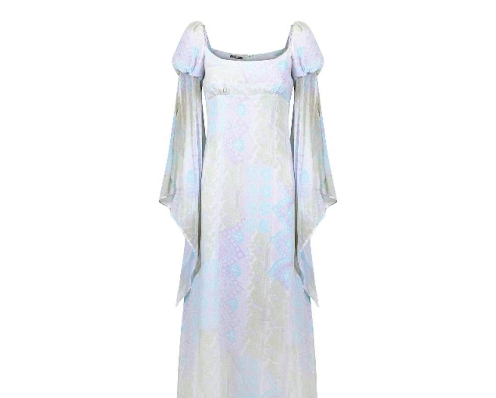 This dramatic late 1960s or early 1970s Quad dress has a really great shape with archetypal Juliet sleeves or Angel wing sleeves. It has a high empire line bust and a floor length A-line skirt. The cotton is a lightweight gauze that is sheer