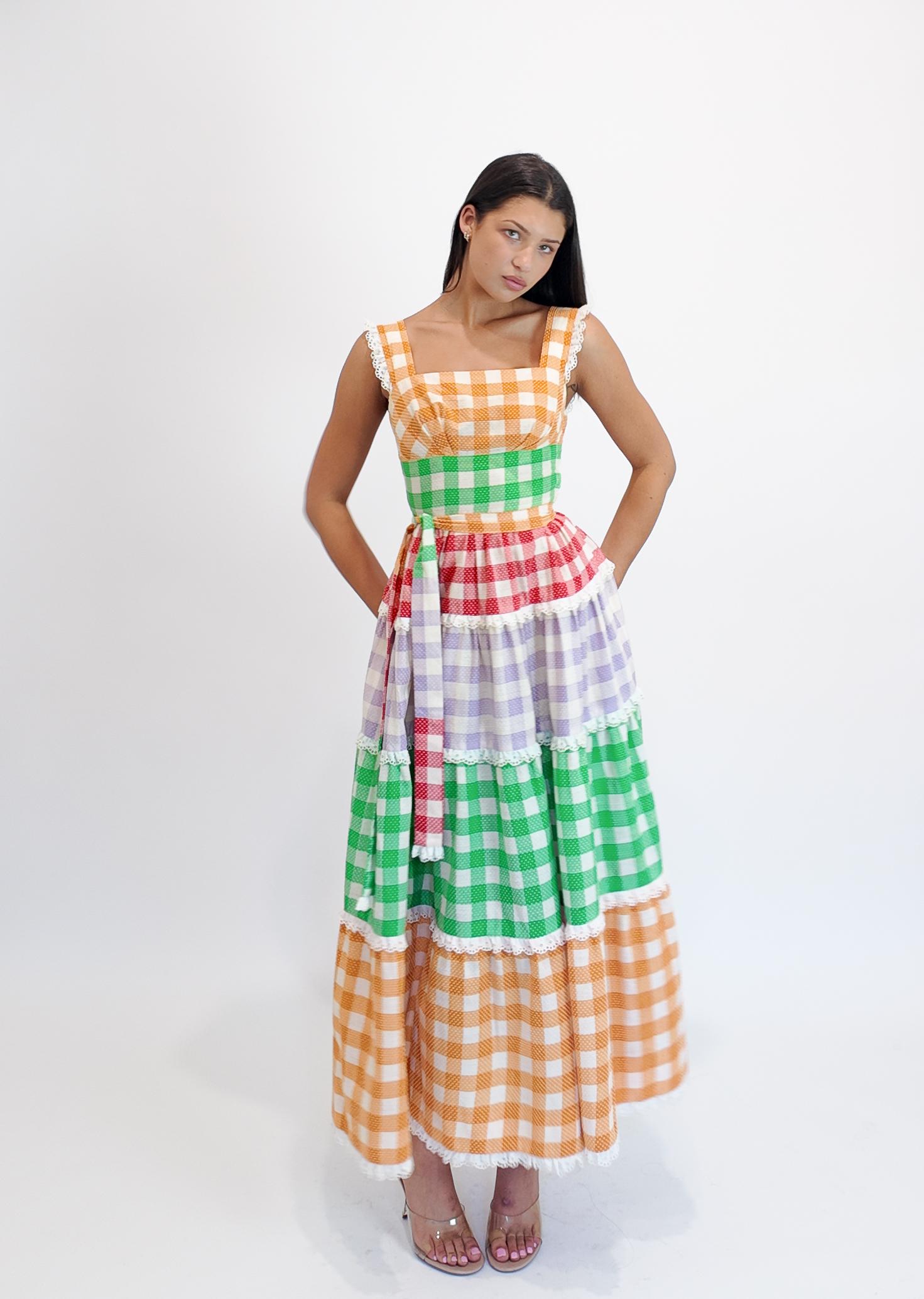 Abbraccia uno stile senza tempo con questo abito in cotone gingham degli anni '70, caratterizzato da una vivace tavolozza multicolore di rosso, viola, verde e arancione. Fabrice in tessuto traspirante, è ideale per le calde giornate estive e gli