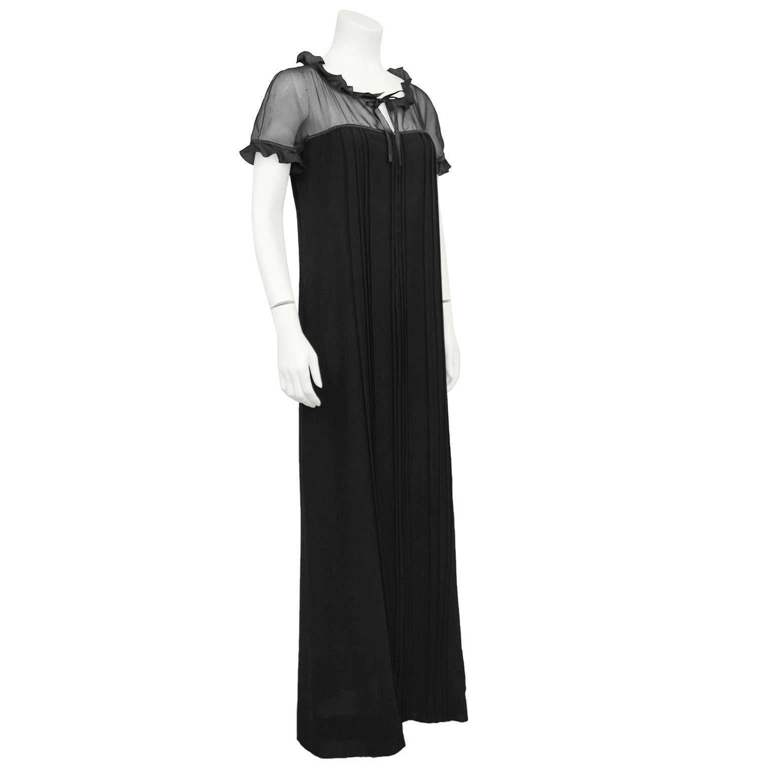 Beautiful 1970s gown by Courreges. Sheer black chiffon yoke and cap sleeves with a black satin ruffle across neckline and hem of sleeves. Tie at neckline creating a small keyhole. The gown then cascades to the floor in black wool with micro stitch