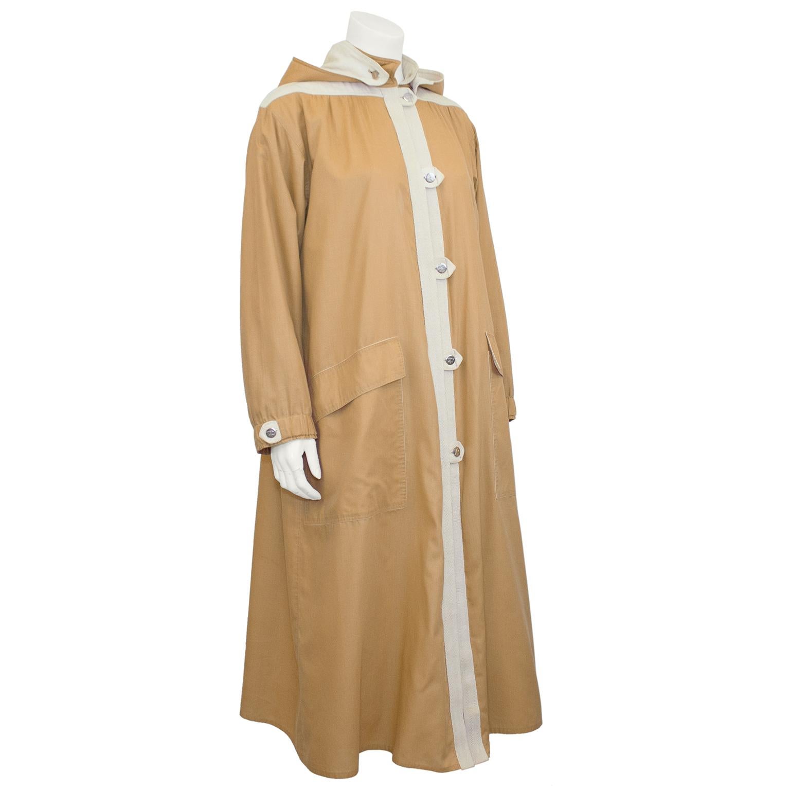 Very chic Courreges car style coat from the 1970s. Coat features long sleeve with elastic at cuffs, Mandarin collar, a removable oversized hood, toggle style button loops with round silver metal buttons and oversized flap pockets. Buttons have
