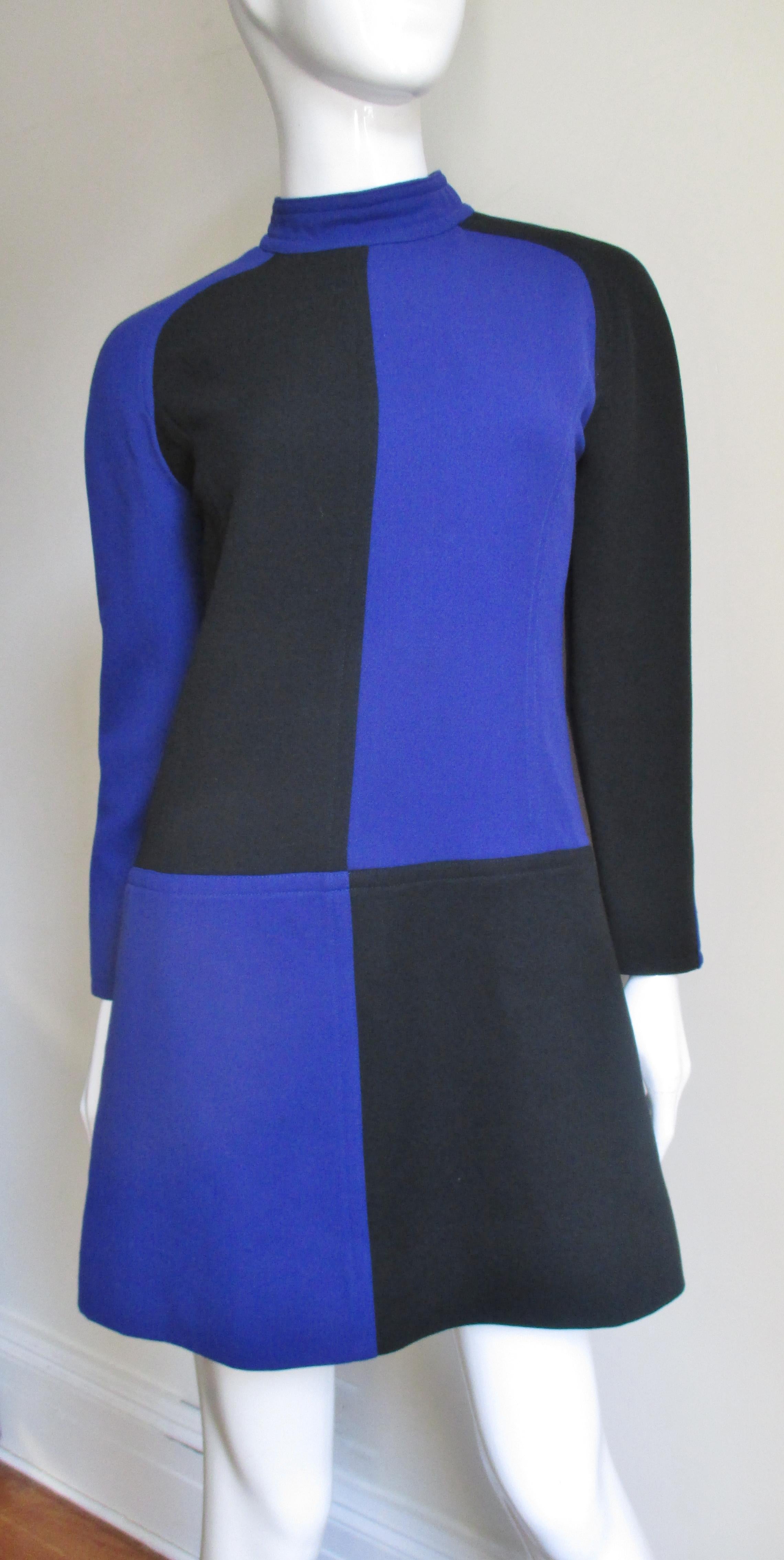 A beautiful color block wool dress alternating panels of black and royal blue from Courreges.  It is an A-line dress flaring subtly to the hem and has a stand up collar, back zipper, raglan sleeves and is fully lined.   
Fits Sizes Extra Small,