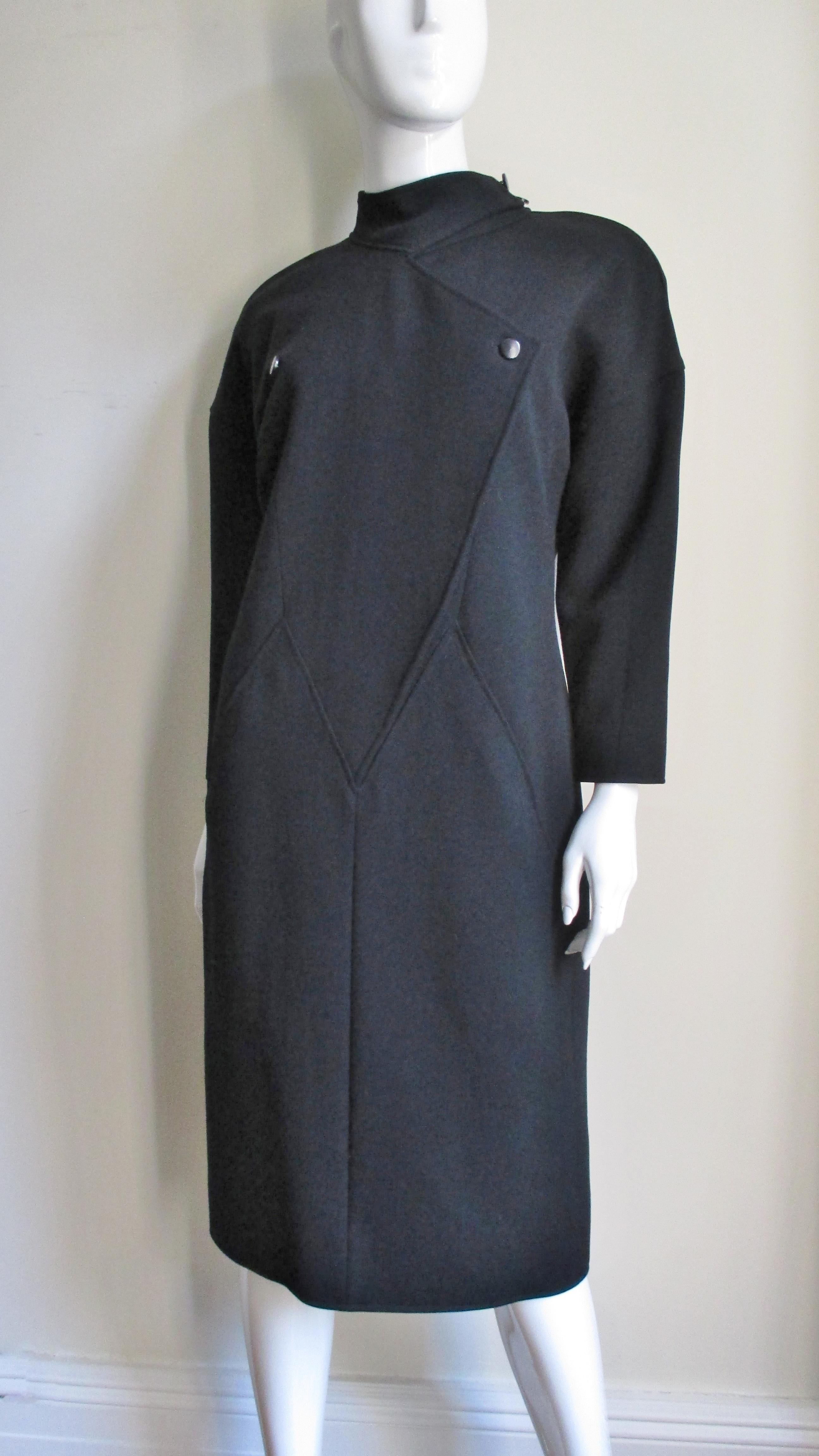 A fabulous black wool dress by Andre Courreges.  It has a stand up collar which buttons on one side, long sleeves, lightly padded shoulders, and 2 front pockets in the seams of the center front. The bodice is joined with the skirt portion by clever