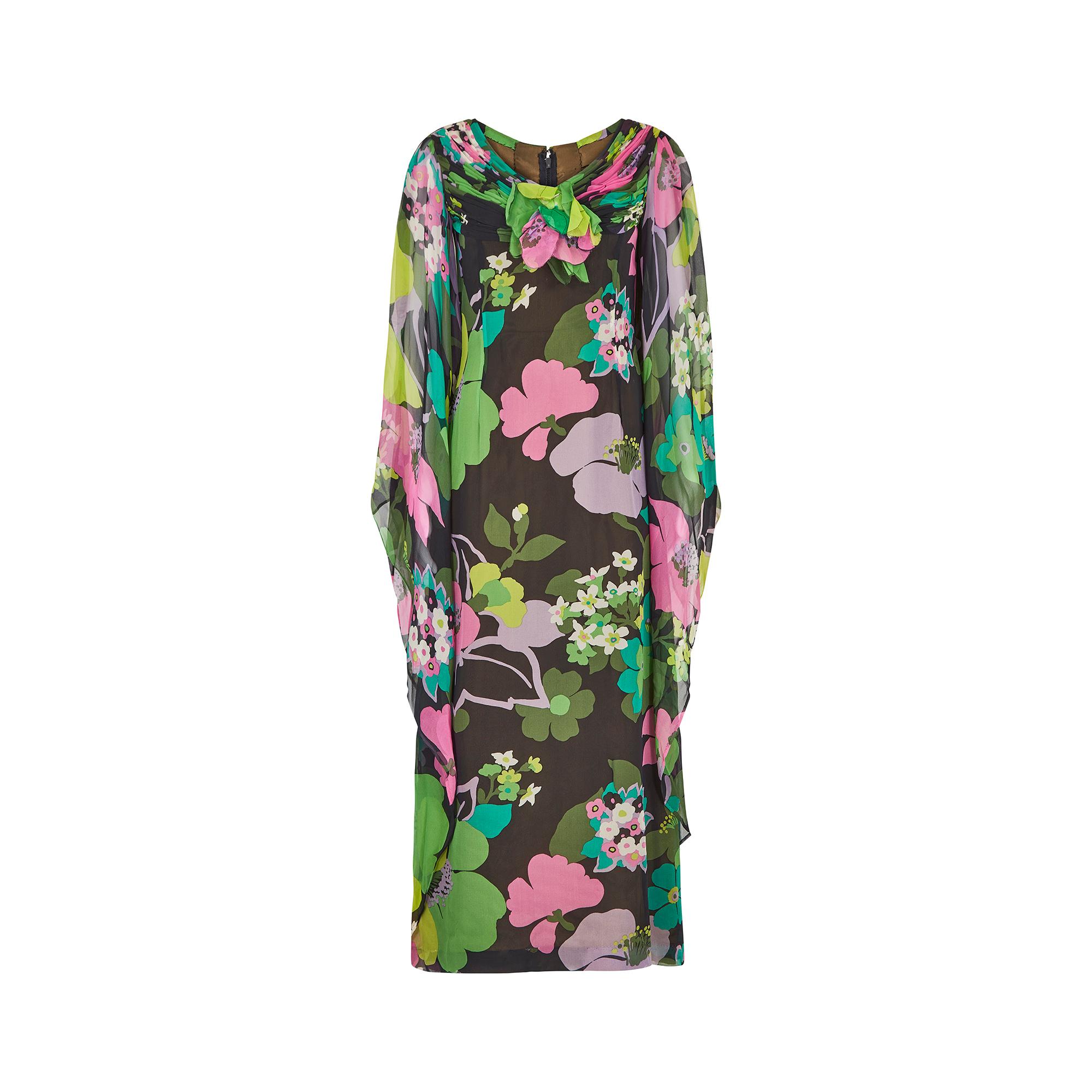 Late 1960s or early 1970s silk chiffon angel sleeve dress with the most magnificent tropical floral print.  The elegant neckline has a series of ruching forming the v-neck that crosses over at the collar bone. There is a large floral applique in the
