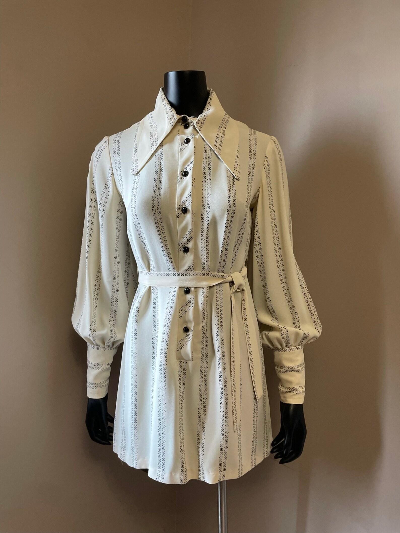 Vintage cream beige and black mini dress
shirt dress styling
exaggerated dagger collar
bishop sleeves
black button front placket & collar
matching sash belt

Circa 1970s
Union Label & Size Label Only
Cream/Black
Cold Rayon
Tagged Size 9
Made in