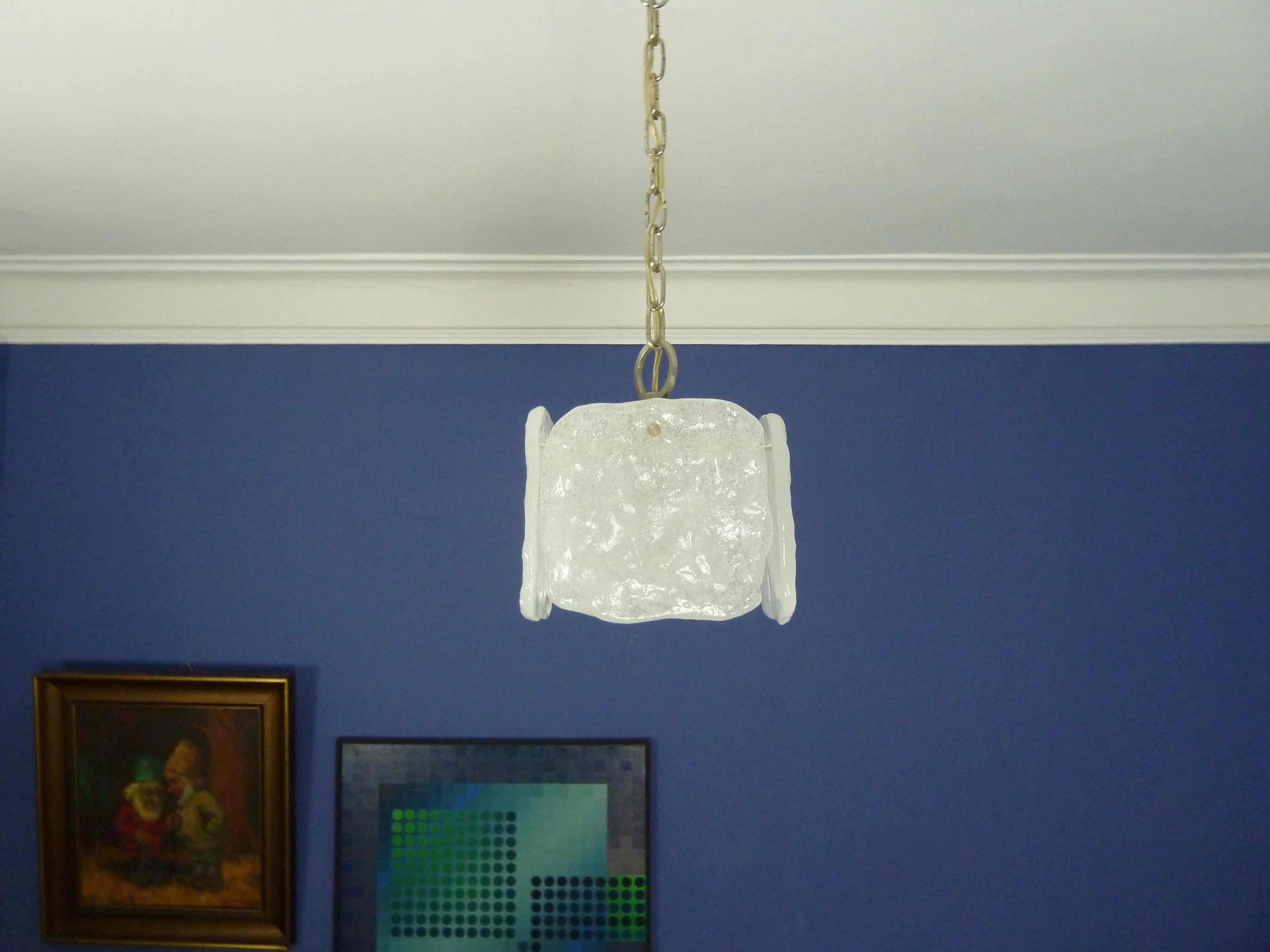 A midcentury 1970s ice-glass modernist pendant 1960s ice glass pendant by Kalmar, Austria.
The handcrafted thick glass tiles are creating beautiful light effects.


The fixture has 1 socket for Edison E27 bulb.
The color and light intensity