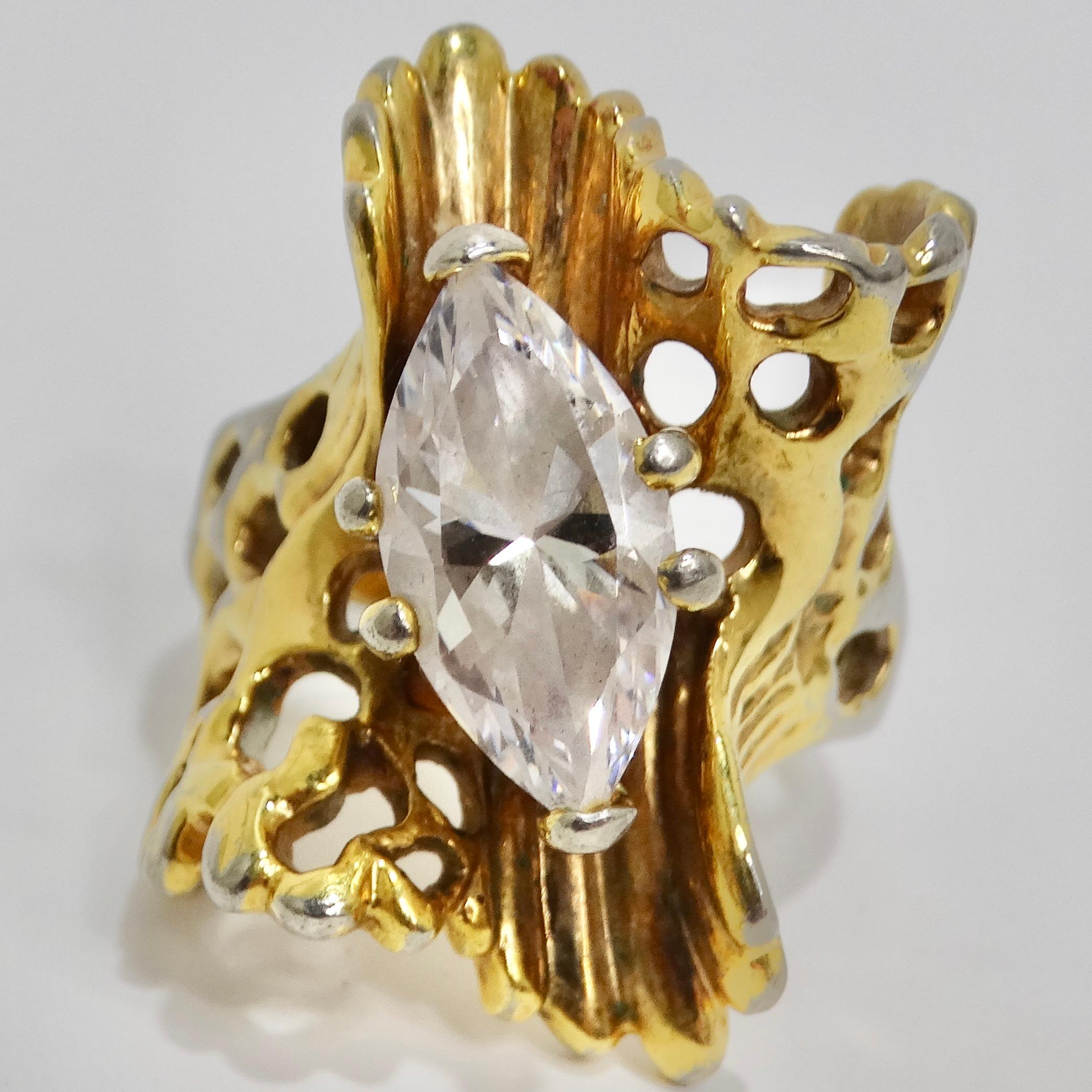 Step into the chic world of the 1970s with our captivating Cubic Zirconia Gold Plated Ring. This eye-catching gold plated silver tone ring boasts a distinctive gold tone motif encircling the synthetic cubic zirconia stone at its center, adding a