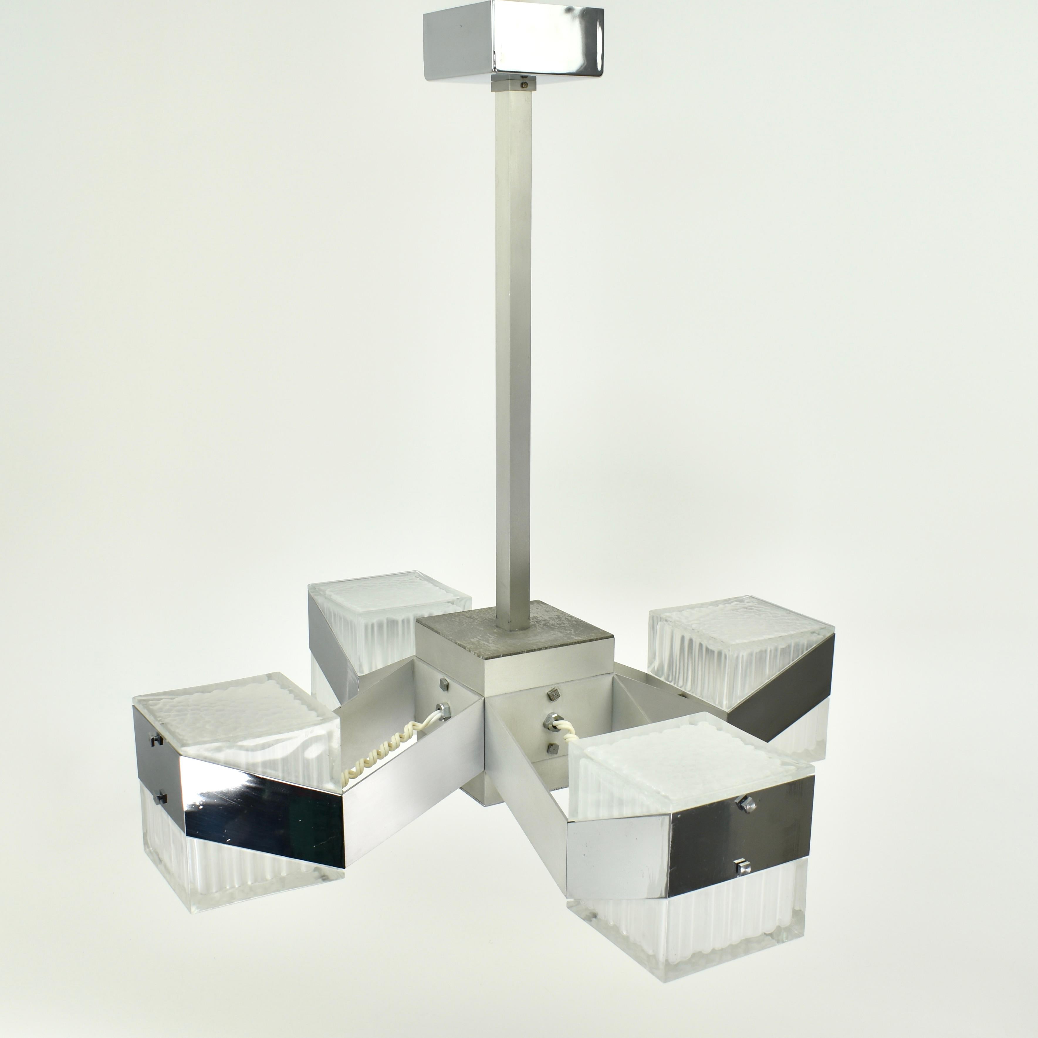 Stupendo lampadario a 4 luci in stile cubista. Realizzata intorno agli anni '70, questa lampada presenta parti cromate, in metallo e in vetro. Ricorda il lampadario cubico di Gaetano Sciolari. La lampada è in ottime condizioni, con una piccola