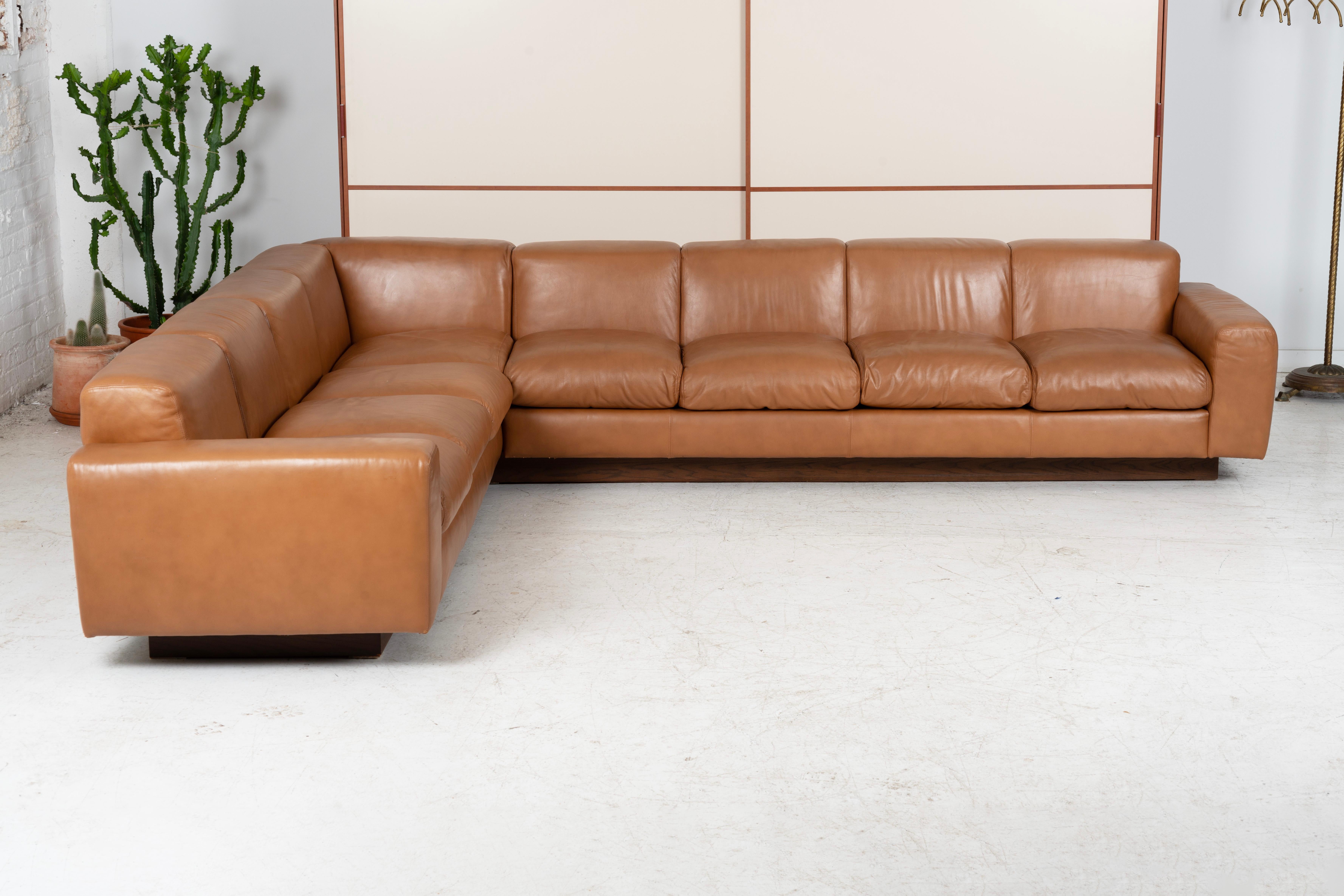 Custom built leather sectional in the 1970's for a home in Chicago. Sofa sits on a connecting walnut plinth base. Leather is in excellent original vintage condition. Seats up to 7. Settee and ottoman are sold and not included in the set.

H: