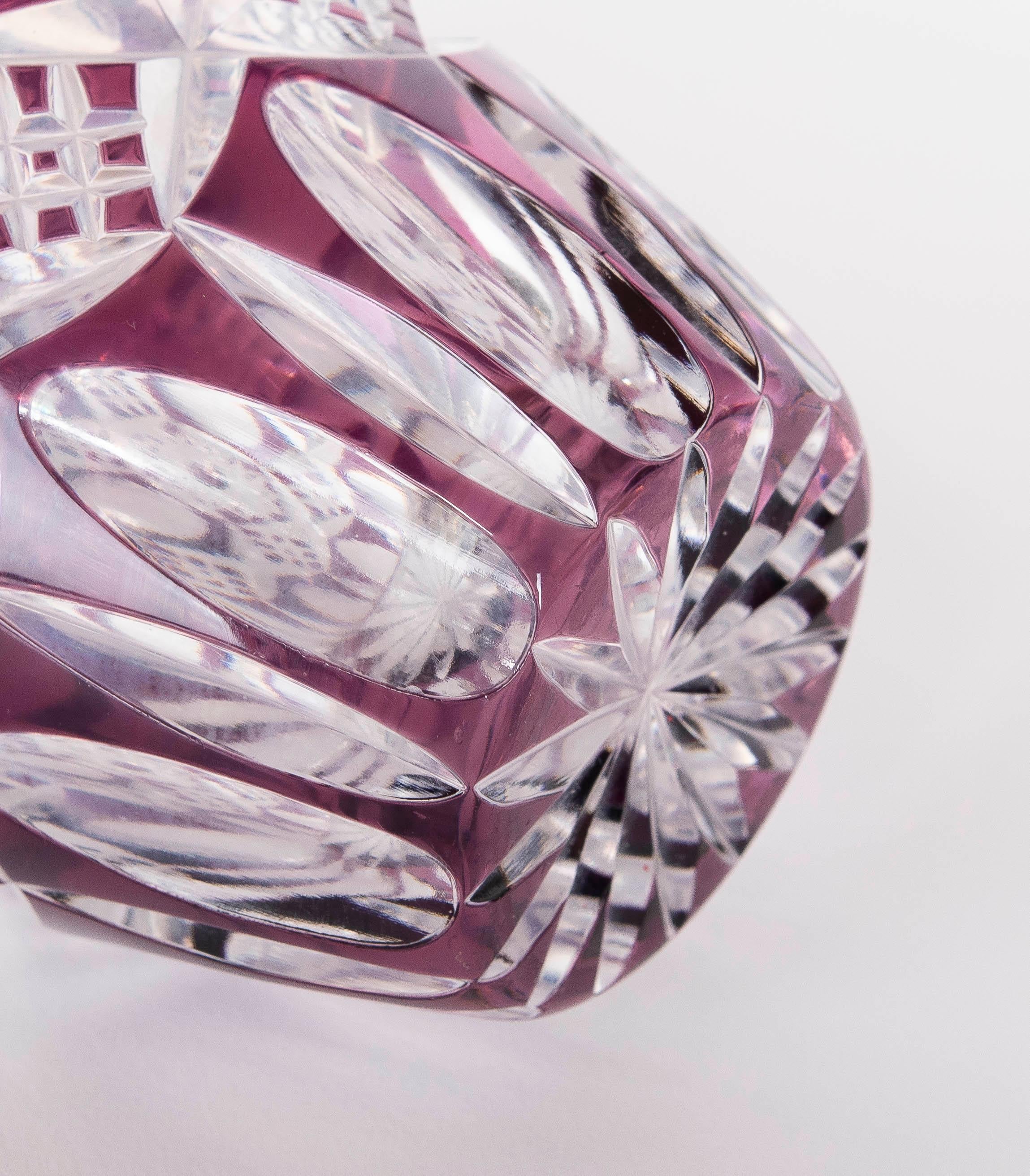 Elegante Vase aus geschliffenem Kristall mit kunstvollem Design, das geometrische und florale Muster kombiniert. Das Stück besticht durch seine filigranen Details und die durchscheinende violette Oberfläche, die ihm einen lebendigen und raffinierten
