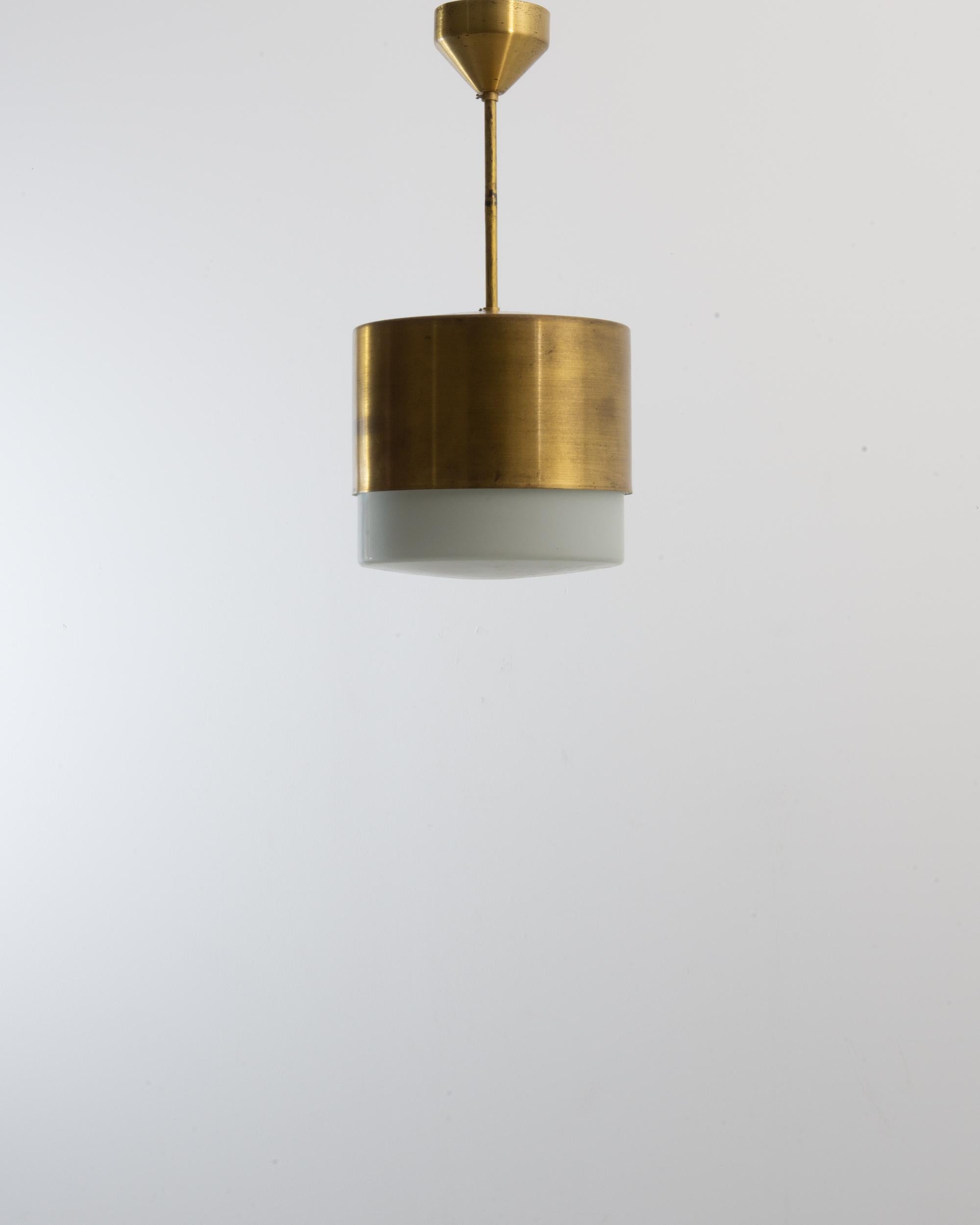 This pendant lamp was produced in Czechia, circa 1970. A vintage gem, this pendant lamp is composed of a gilded brass shade with a discreet brushed finish and a light patina. An opal glass bulb is lodged in the wide cylindrical shade, elegantly