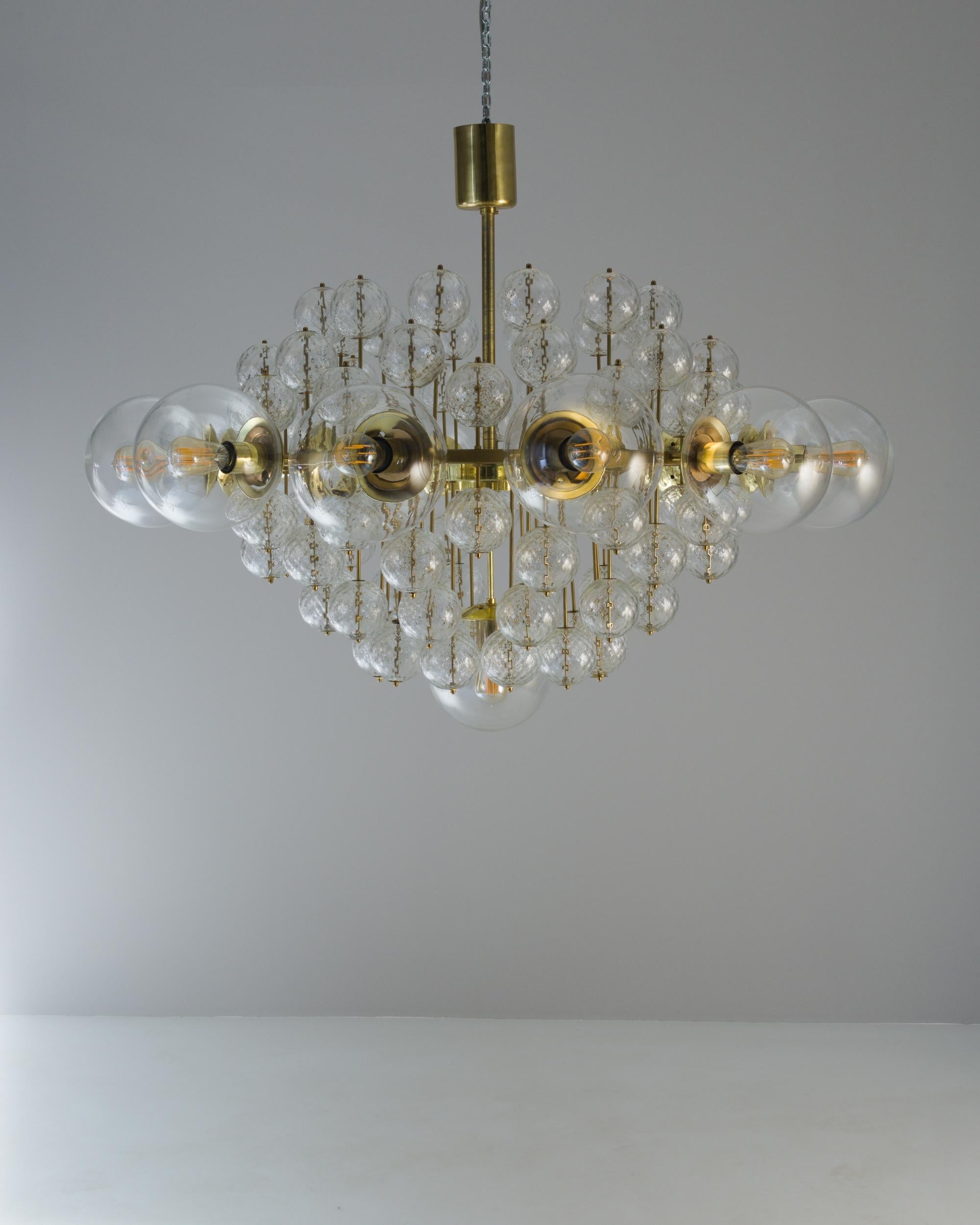 A metal and glass chandelier made in 1970s Czechia. Blending both mid-century and Art Deco sensibilities, this illustrious and mesmerizing chandelier exudes a chic and inspiring energy. With numerous, clustered glass balls blooming from the center