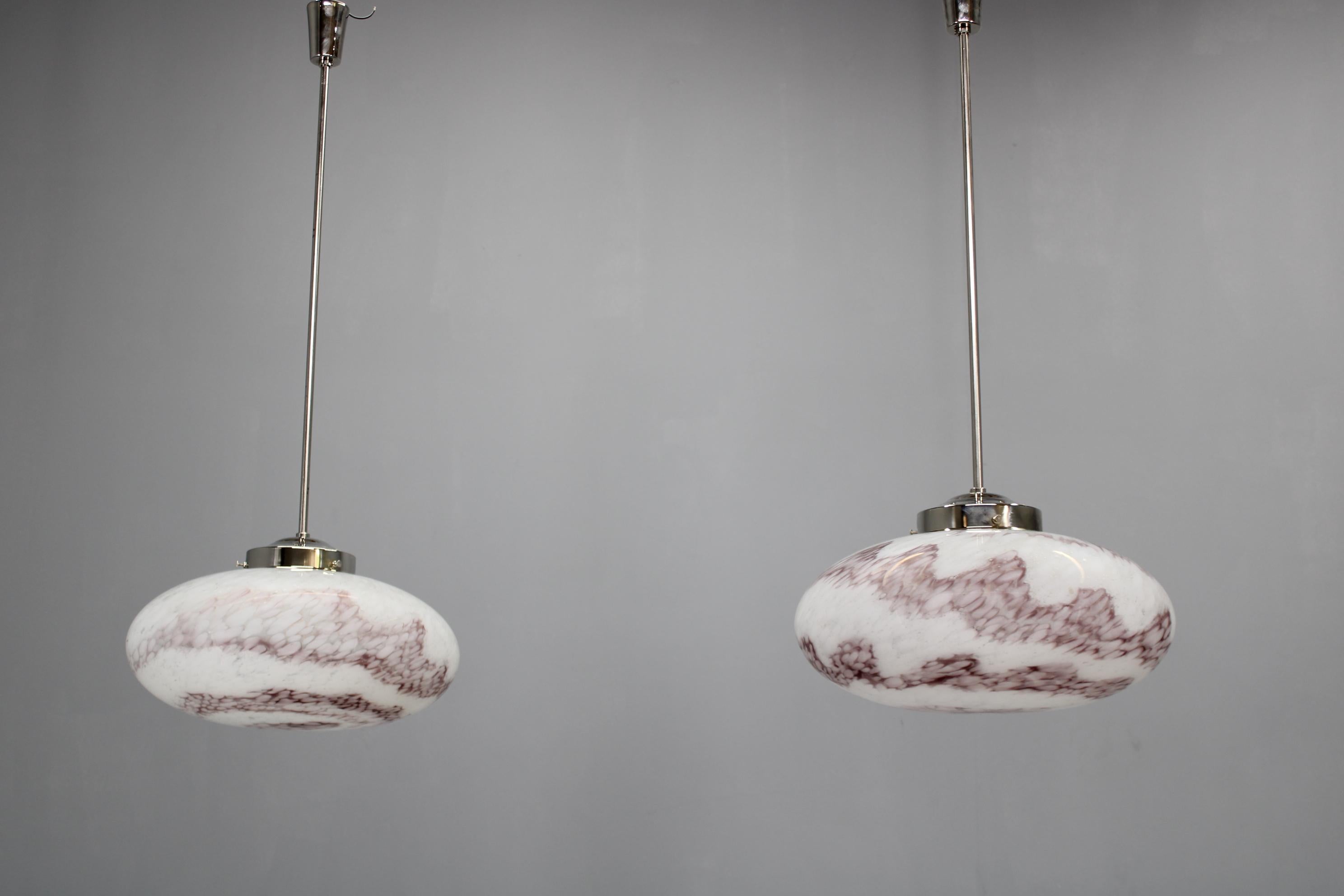 Este par de lámparas colgantes de mediados de siglo de la década de 1970 procede de Kamenický Šenov, el histórico centro checo de fabricación de vidrio artístico. Cada colgante combina un soporte de metal cromado con una hermosa pantalla de cristal