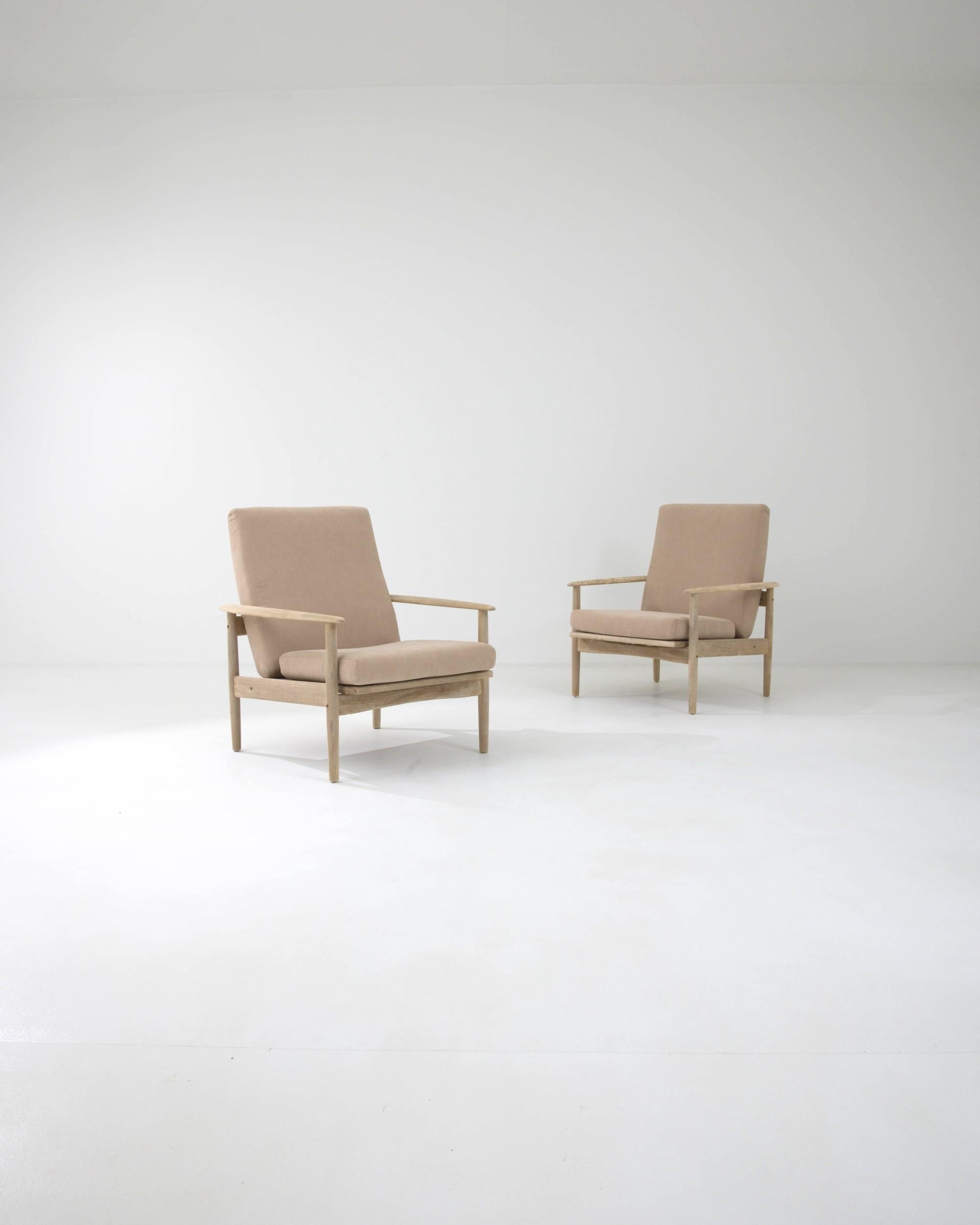 This attractive pair of vintage armchairs combine a stylish Modernist silhouette with a soothing color palette. Made in Czechia in the 1970s, the clean lines of the wooden frame are softened by gently rounded armrests and the arched contour of the
